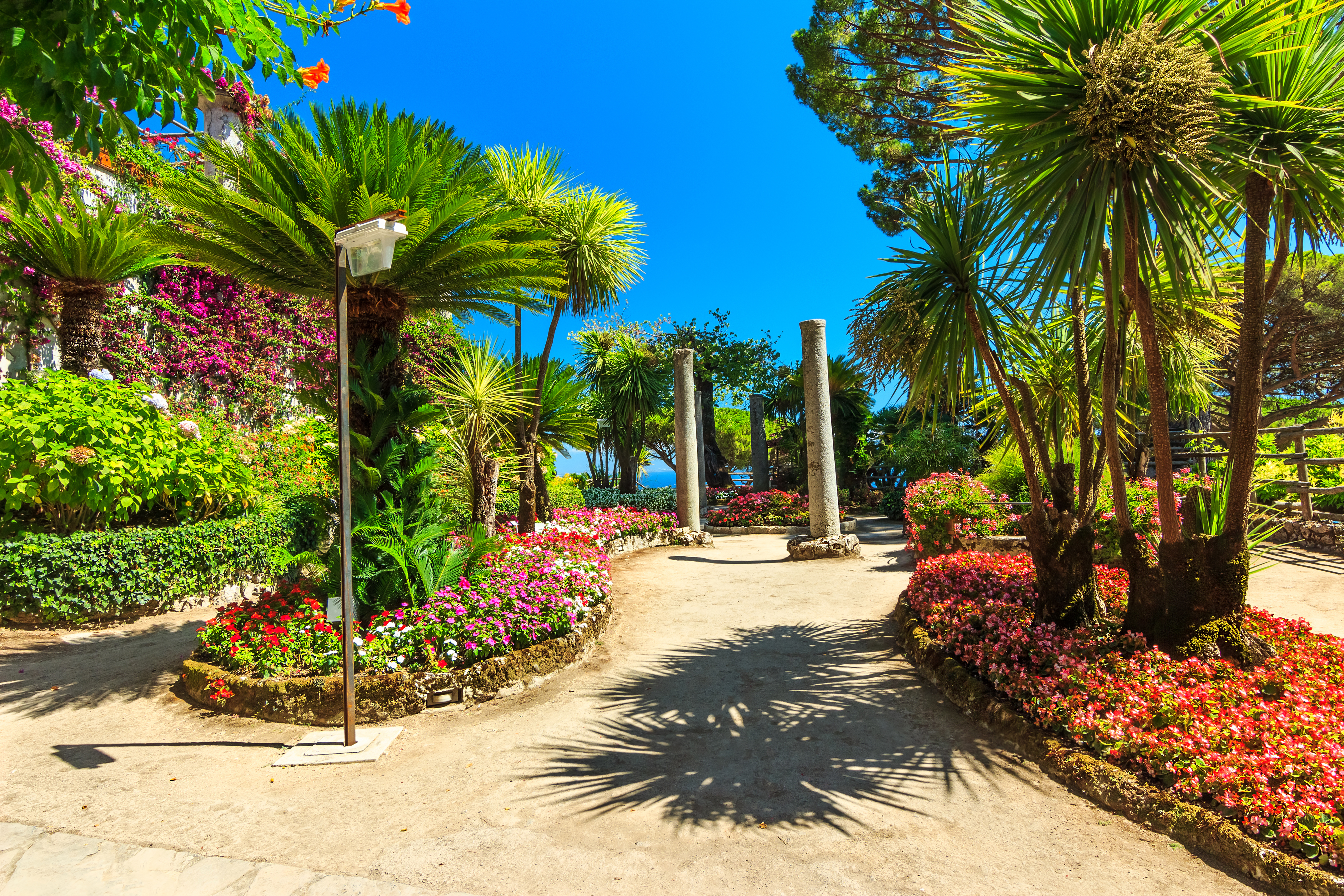 Fascinerende romantisk blomsterhave med frodig vegetation og dekorative søjler på Villa Rufolos berømte terrasser i Ravello, der byder på en betagende udsigt over den smukke Amalfikyst i Italien
