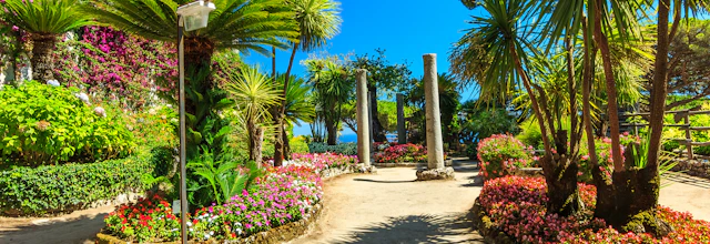 Fascinerende romantisk blomsterhave med frodig vegetation og dekorative søjler på Villa Rufolos berømte terrasser i Ravello, der byder på en betagende udsigt over den smukke Amalfikyst i Italien