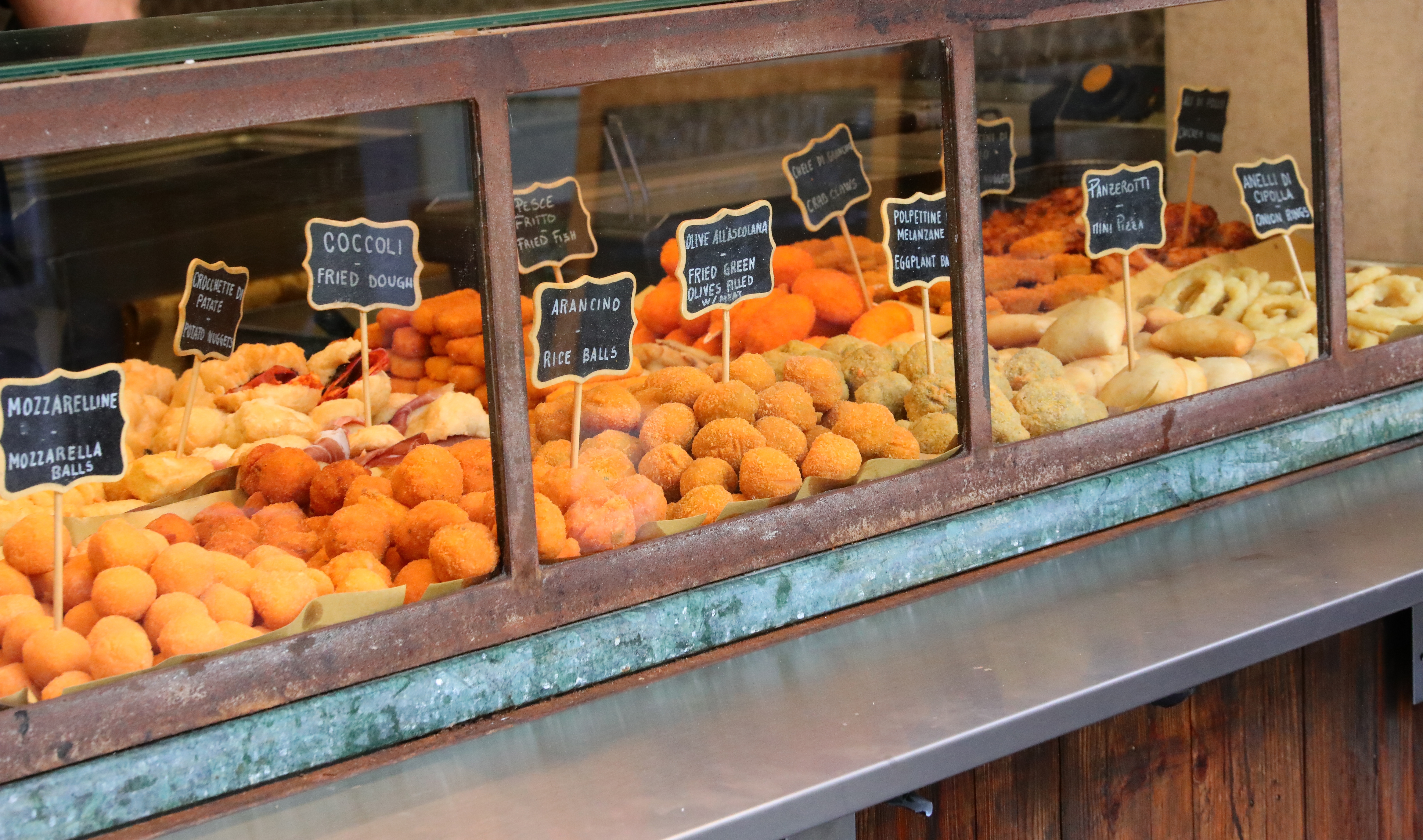 Italiensk streetfood butik med arancini risboller, coccoli og mozzarellakugler bag glasmontre i en traditionel syditaliensk madbod