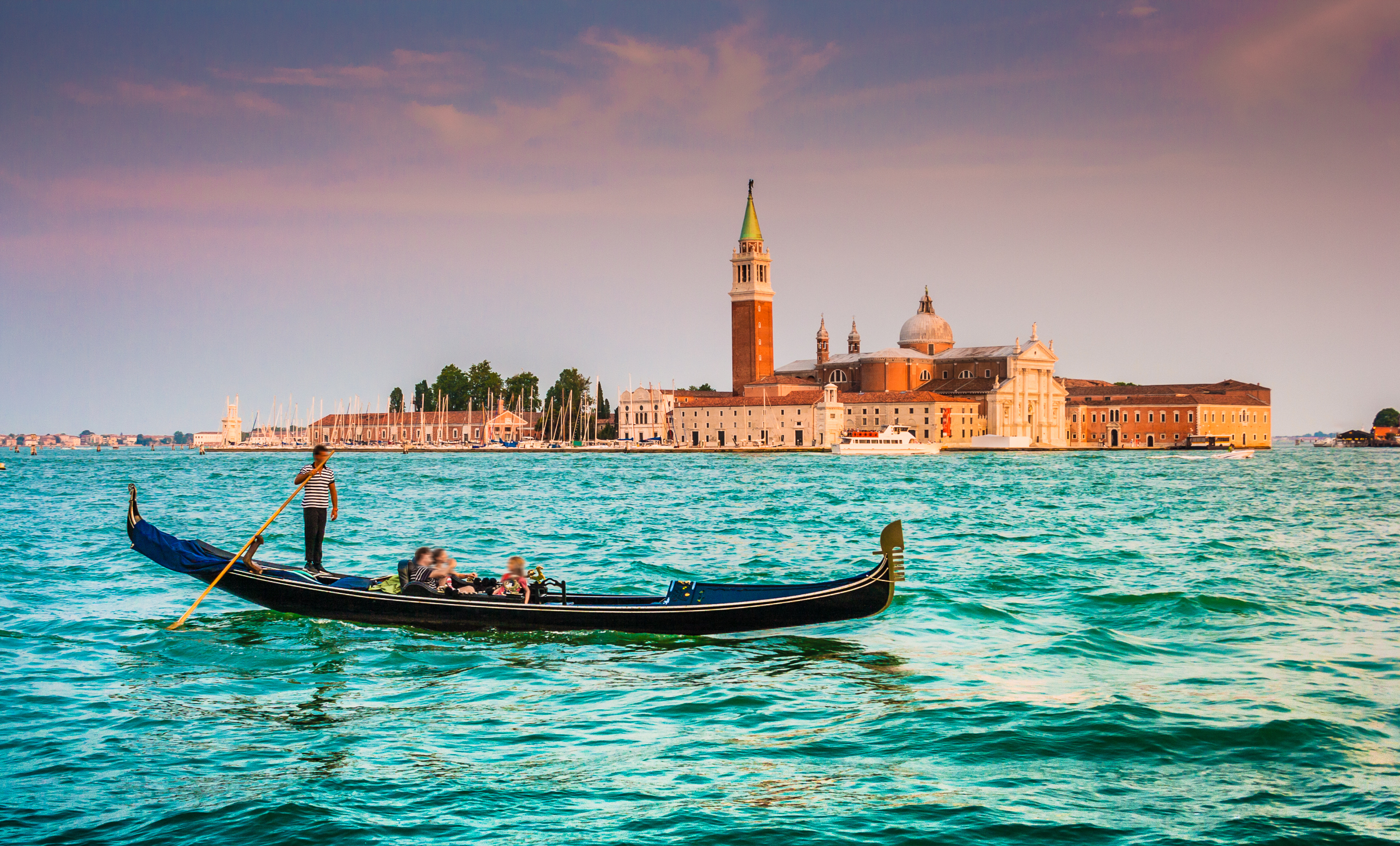 Traditionel gondoltur i Venedig Italien med udsigt til historisk basilika og høje campanile