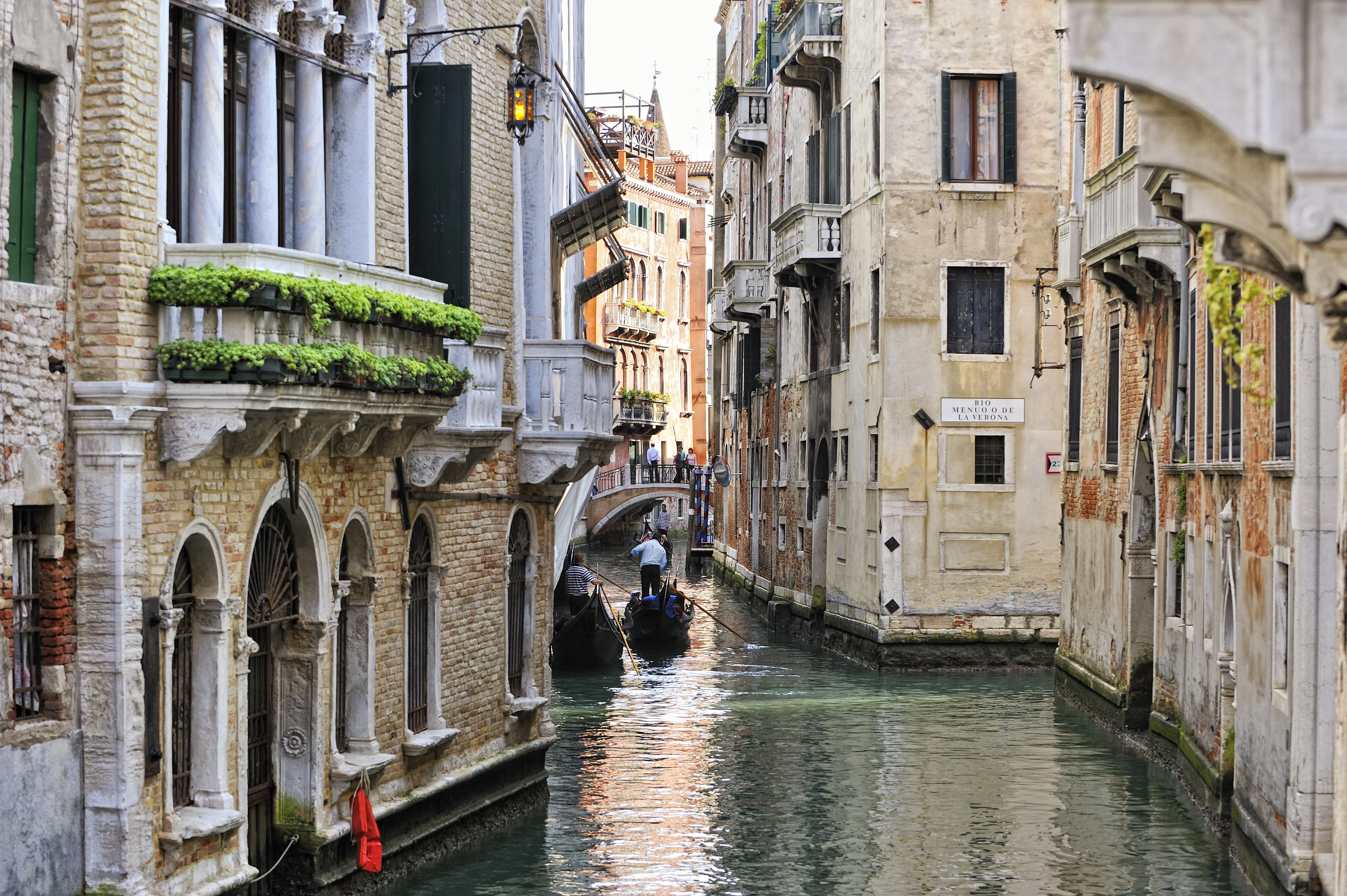 Autentisk venetiansk gondol navigerer gennem smal kanal mellem historiske italienske bygninger