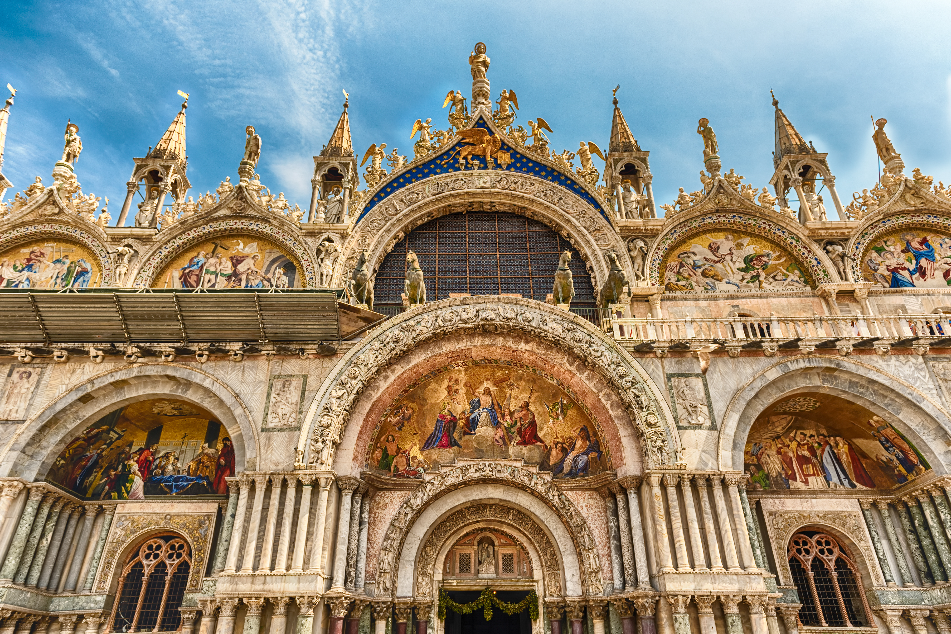 Markusdomens imponerende facade med buede indgange og kunstvaerk i Venedig