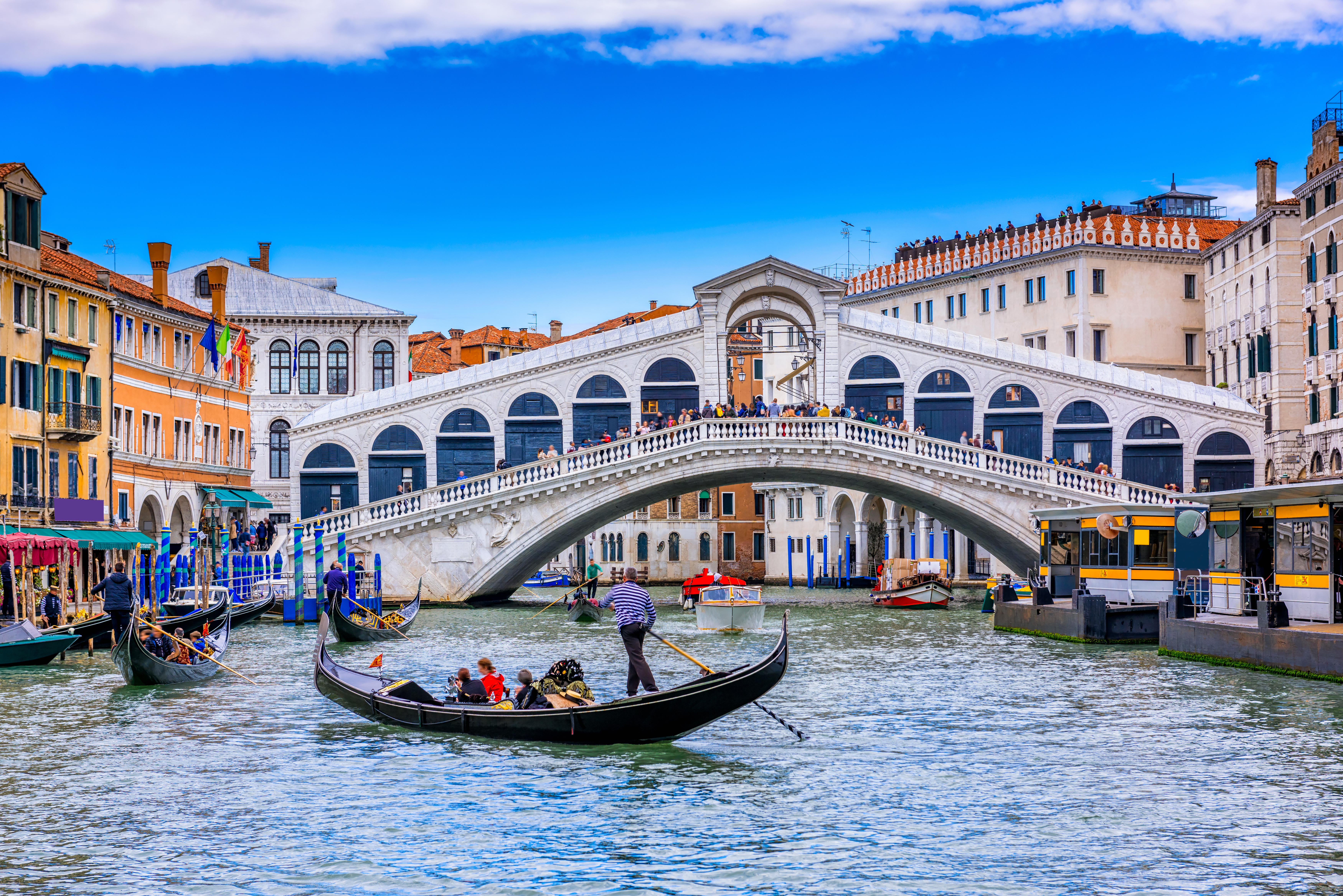 Gondolier roer turister langs Canal Grande i Venedig forbi den berømte Rialto Bro på en smuk sommerdag