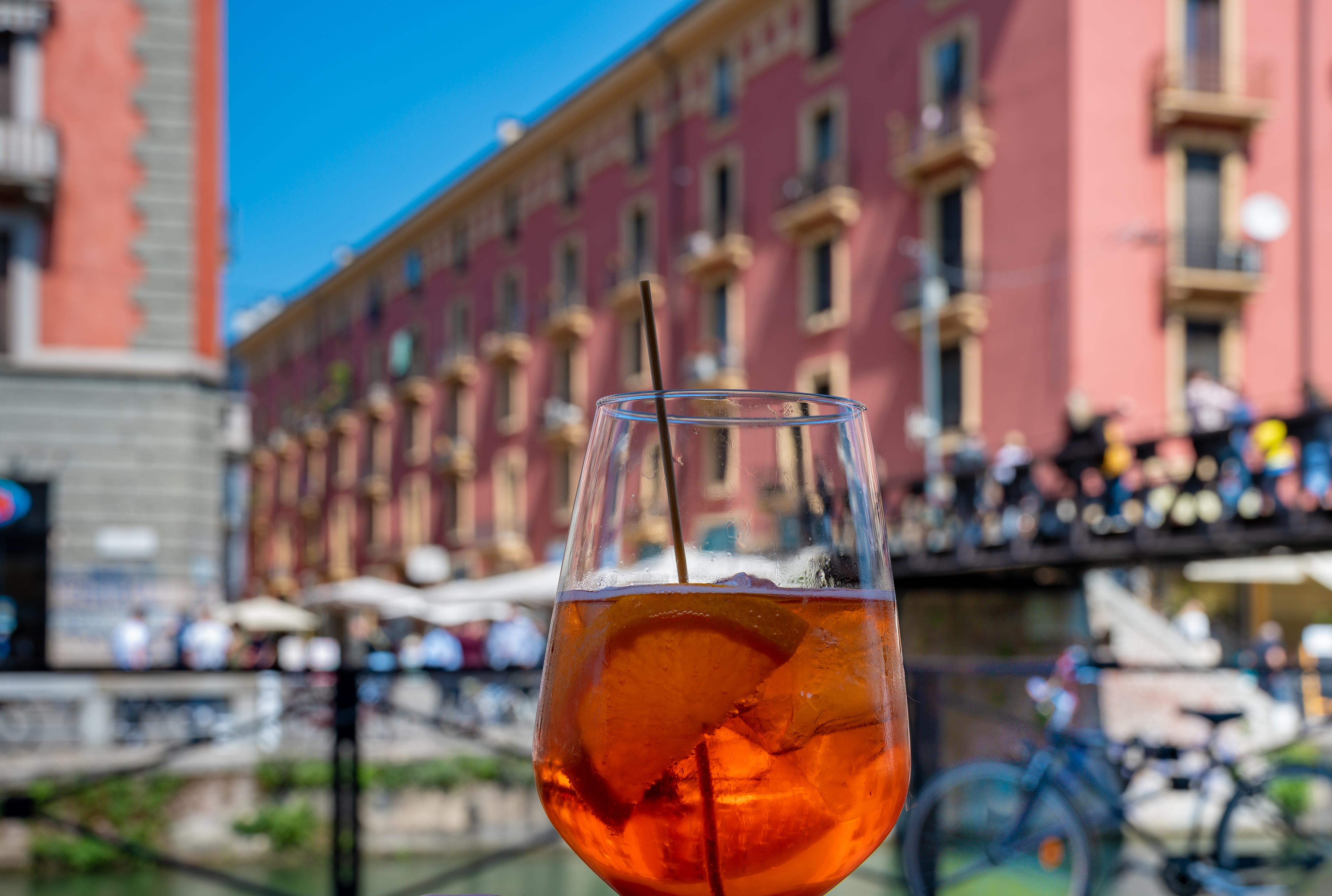 Italiensk aperitif cocktail med orange farve foran pittoreske røde italienske bygninger