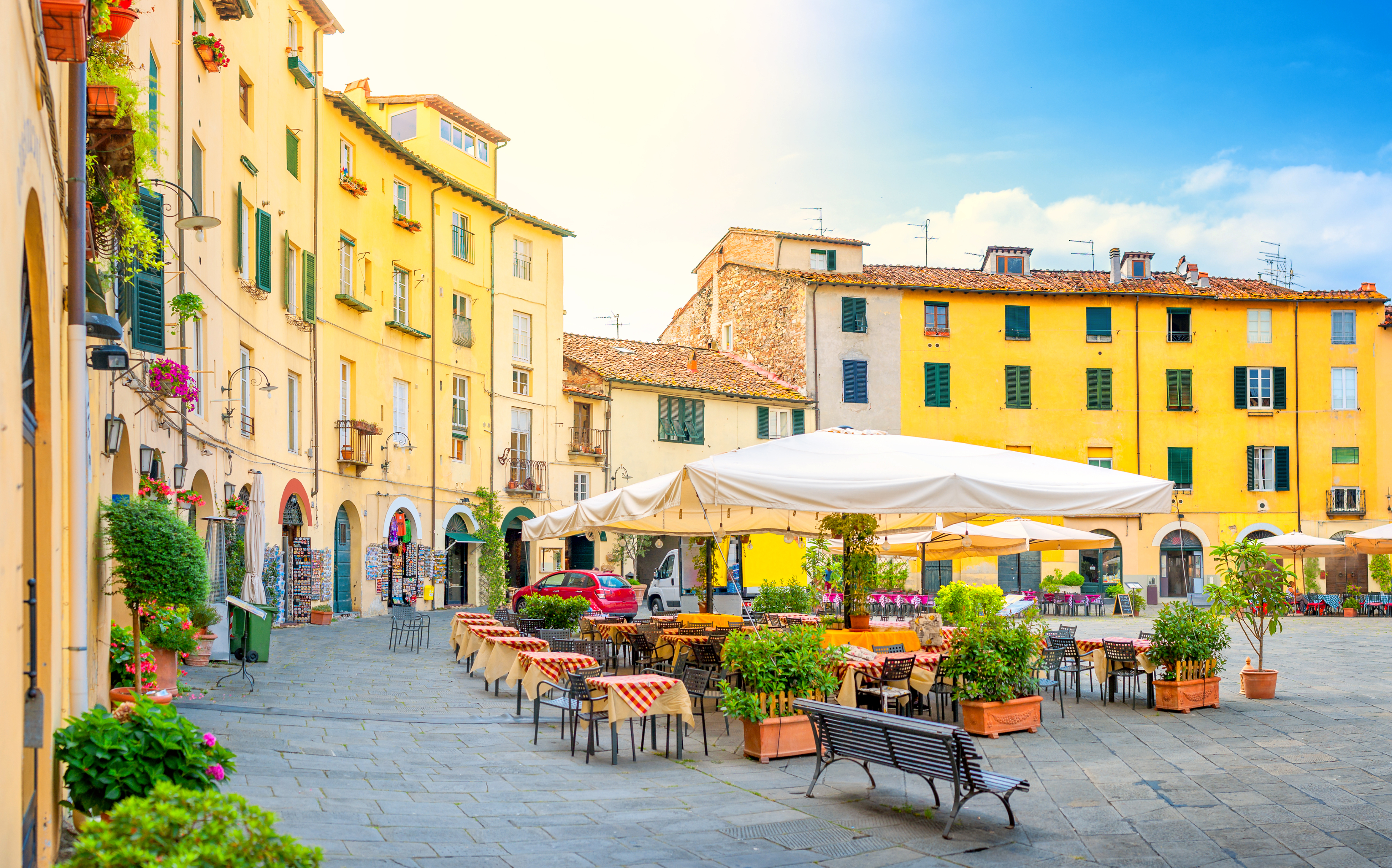 Smuk italiensk plads med restaurant terrasse og karakteristiske gule huse om sommeren