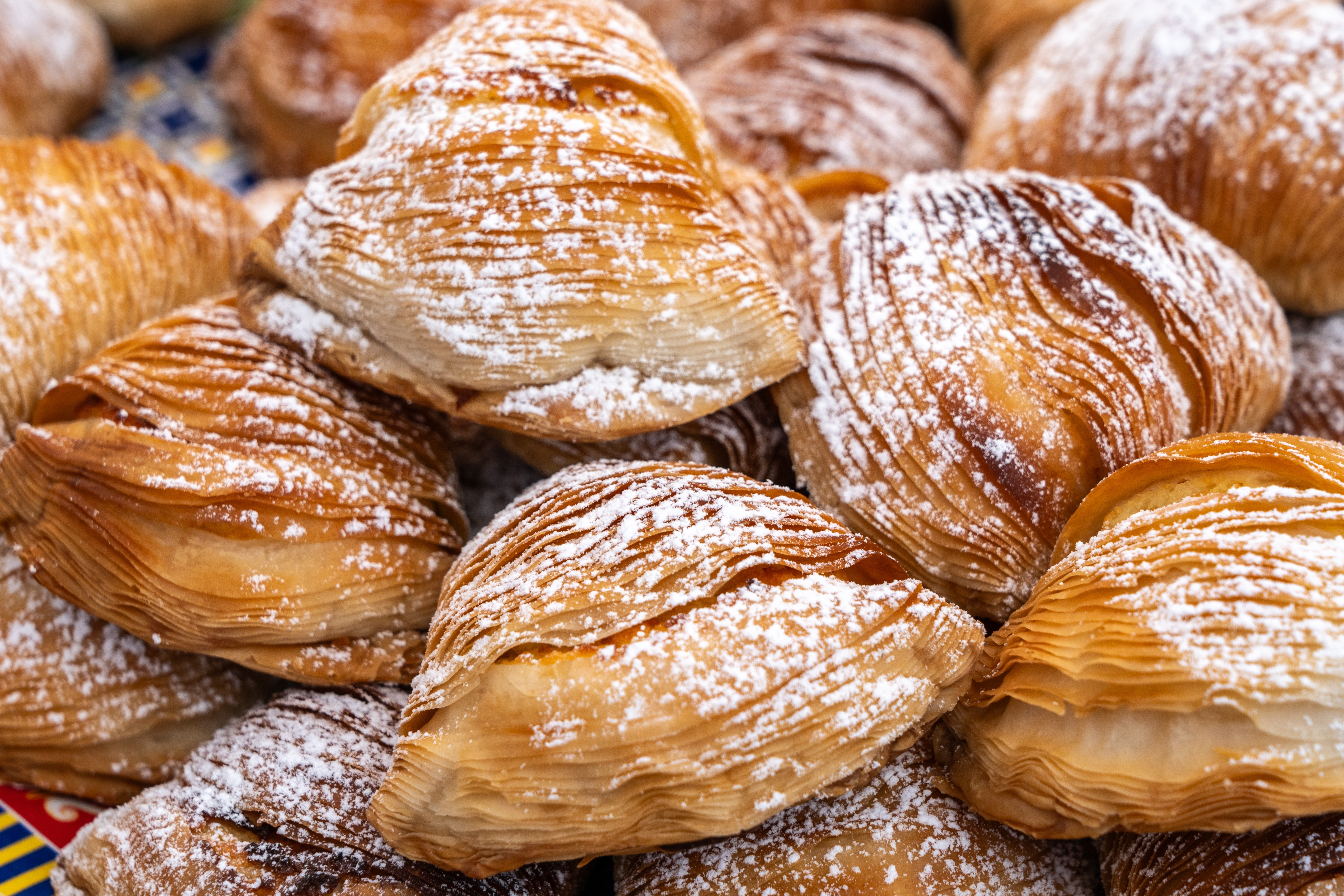 Lækre friskbagte sfogliatella-kager med gyldne sprøde lag og flormelis fra et marked i Napoli