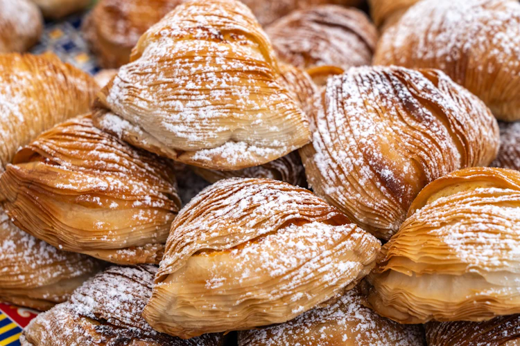 Lækre friskbagte sfogliatella-kager med gyldne sprøde lag og flormelis fra et marked i Napoli