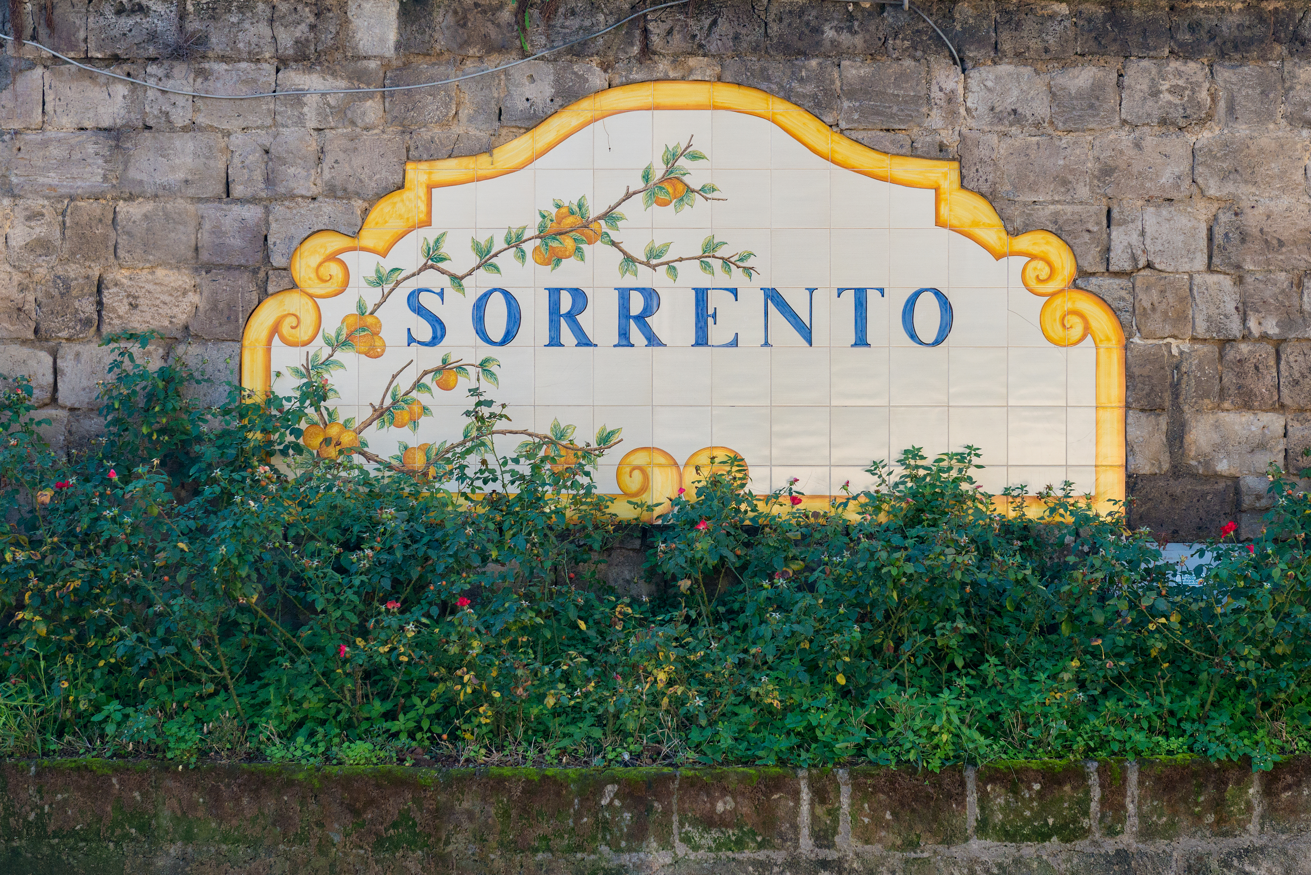 Italiensk Sorrento skilt med citrus dekoration på traditionel stenmur