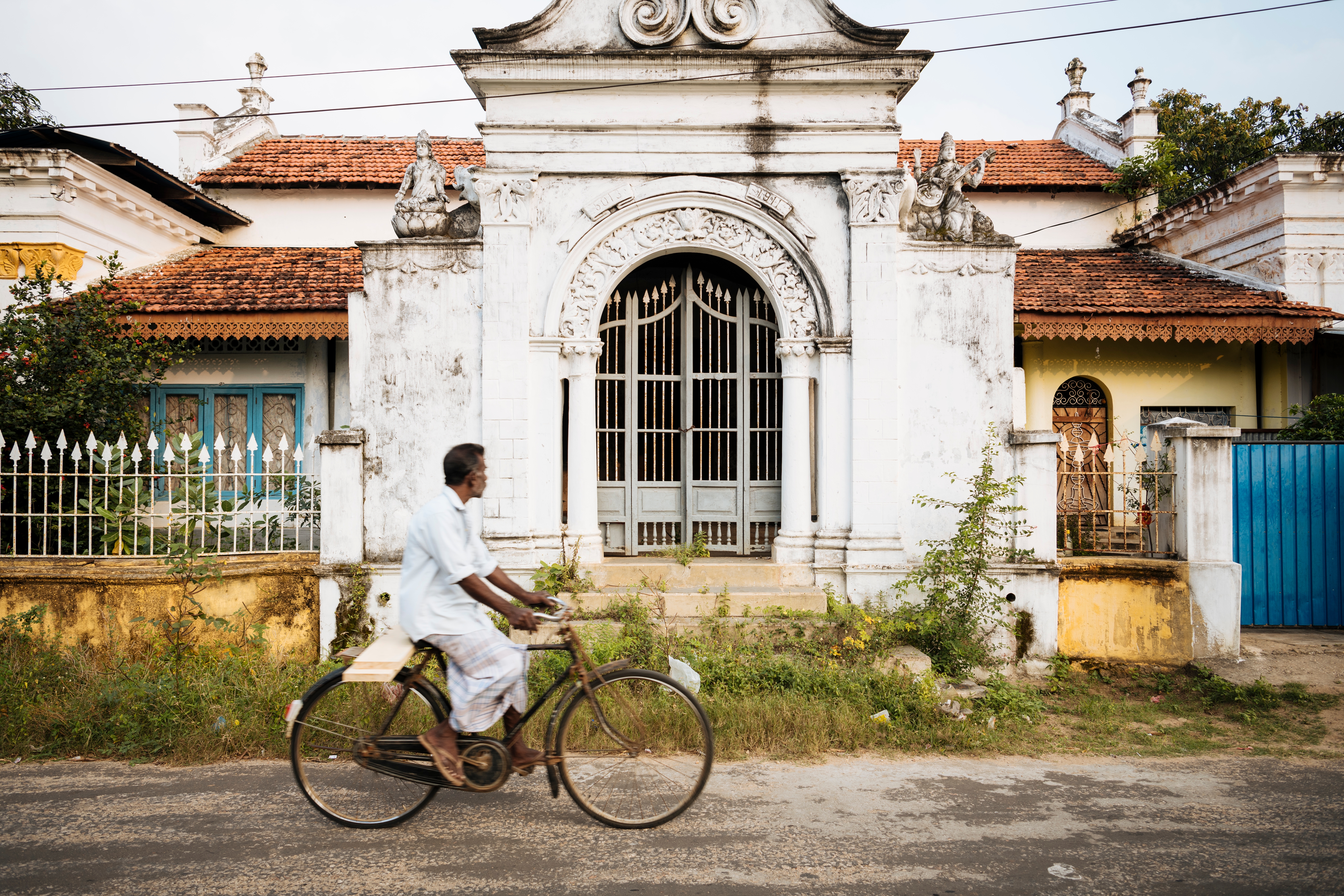 Lokal cyklist passerer dekorativ hvid port i Jaffna, Sri Lanka