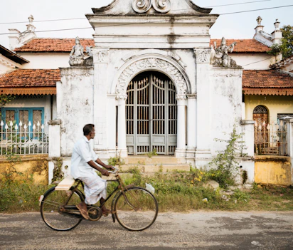 Lokal cyklist passerer dekorativ hvid port i Jaffna, Sri Lanka