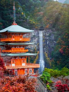 Smuk orangerød pagoda ved Kumano Nachi Taisha helligdommen med det 133 meter høje Nachi vandfald og farverig efterårsskov