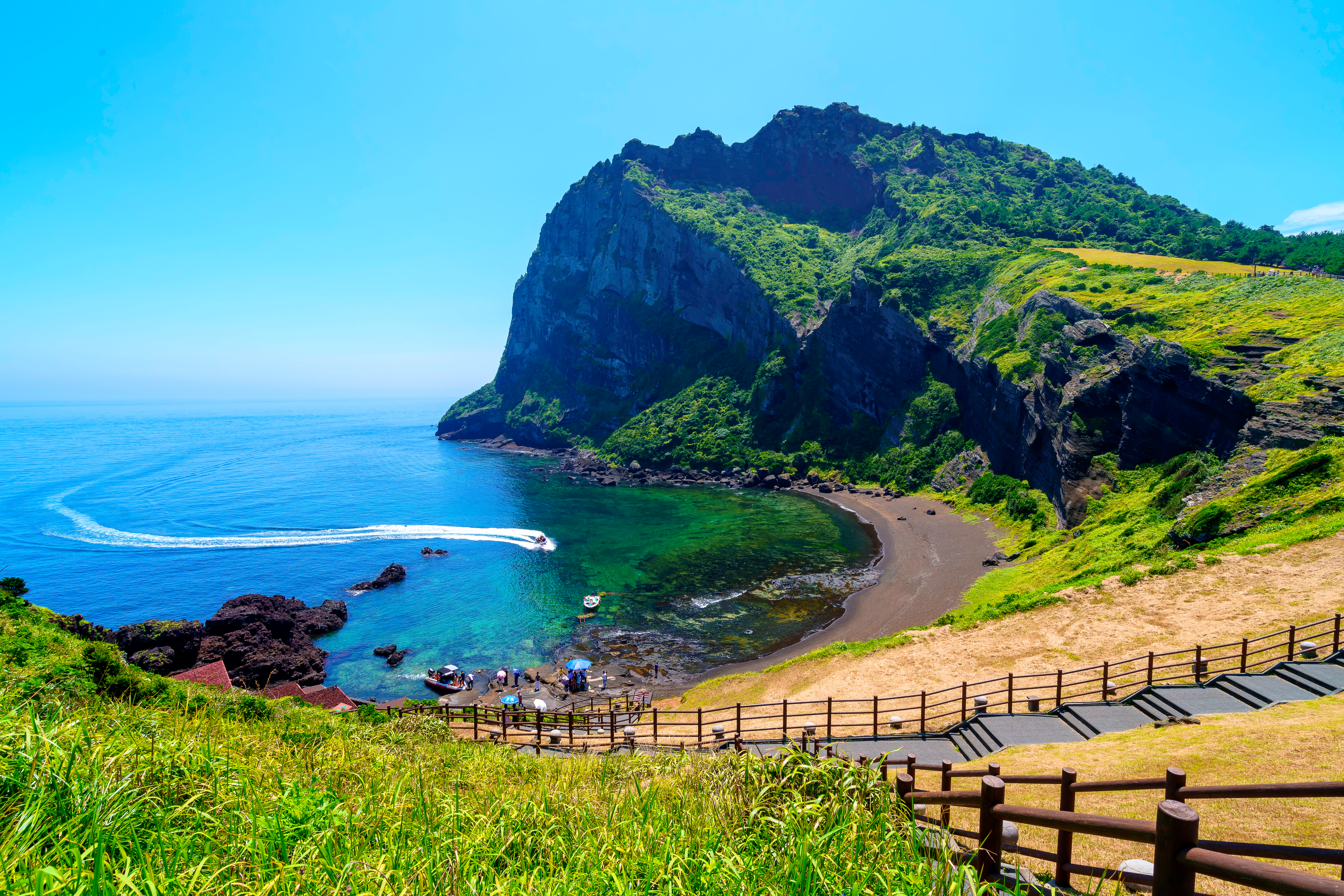 Naturskøn udsigt over Seongsan Ilchulbong vulkanbjerget på Jeju Island med en idyllisk bugt med turkist vand og sort sandstrand i Sydkorea