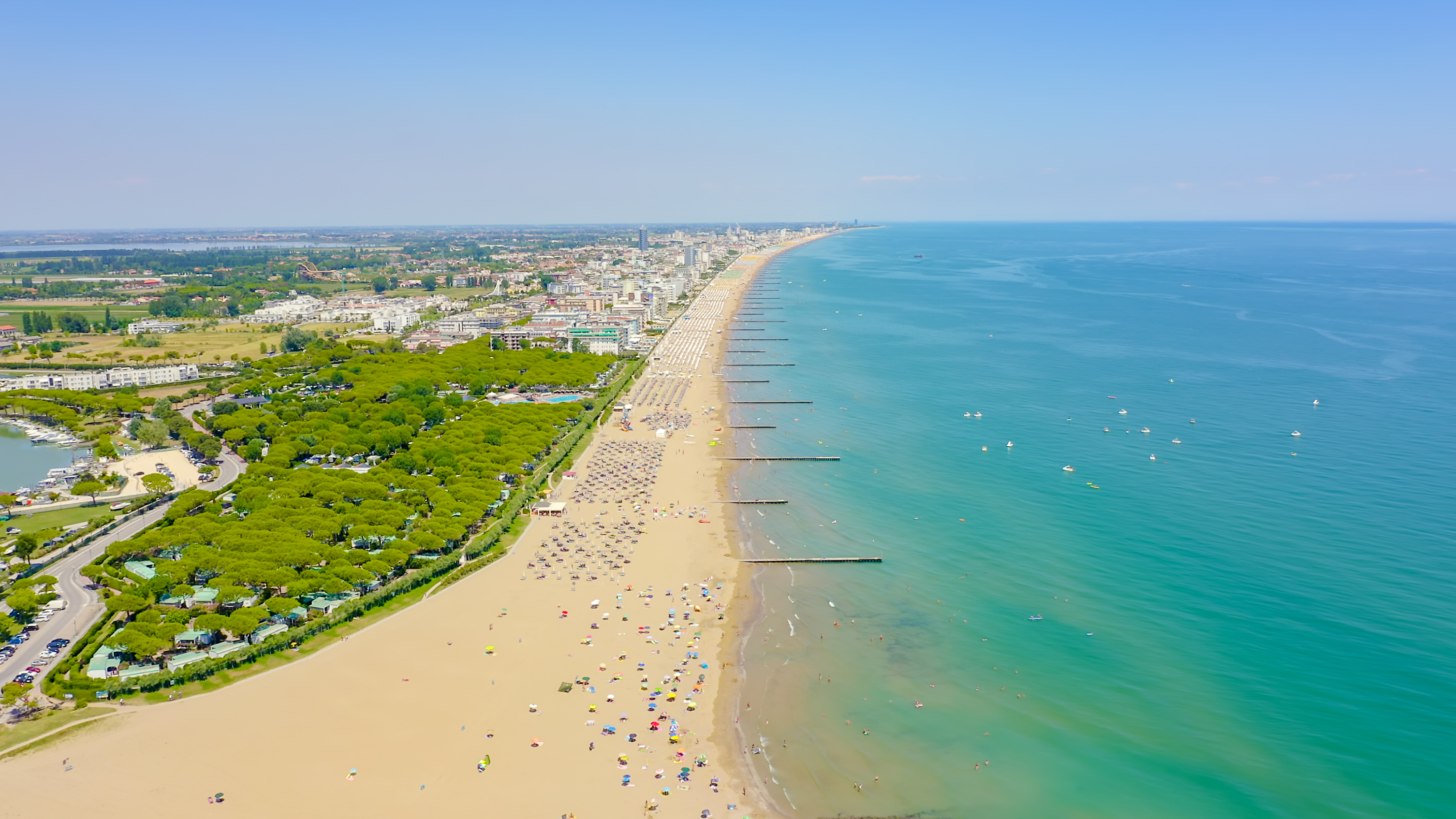 Fuglefoto af Lido di Jesolo stranden i det nordlige Italien med solbadende turister, farverige strandparasoller og det smukke turkise Adriaterhav