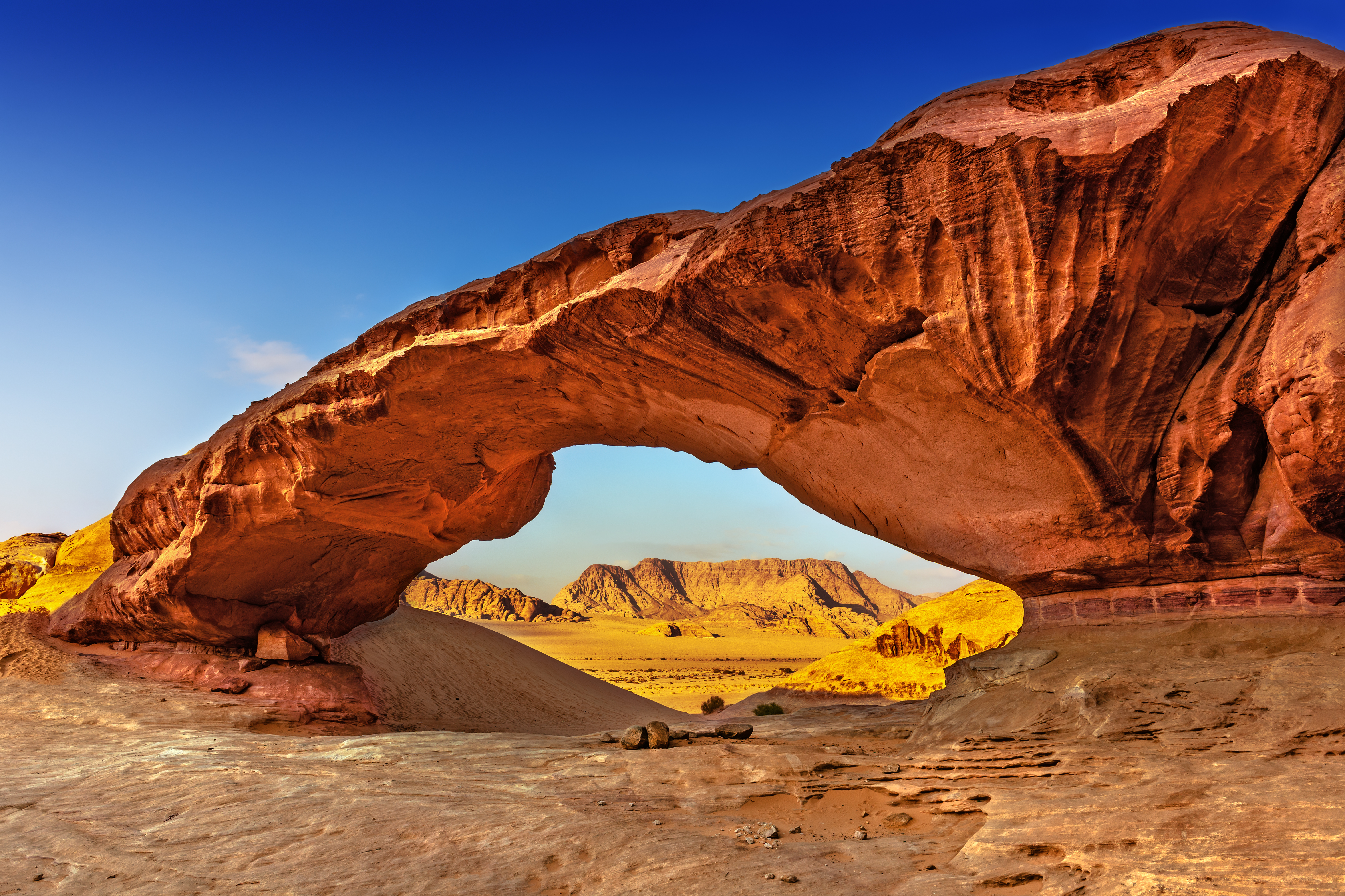 Imponerende udsigt fra en naturlig klippeport i den røde Wadi Rum-ørken i Jordan, der viser det fortryllende landskab af sandsten og klitter i Mellemøsten