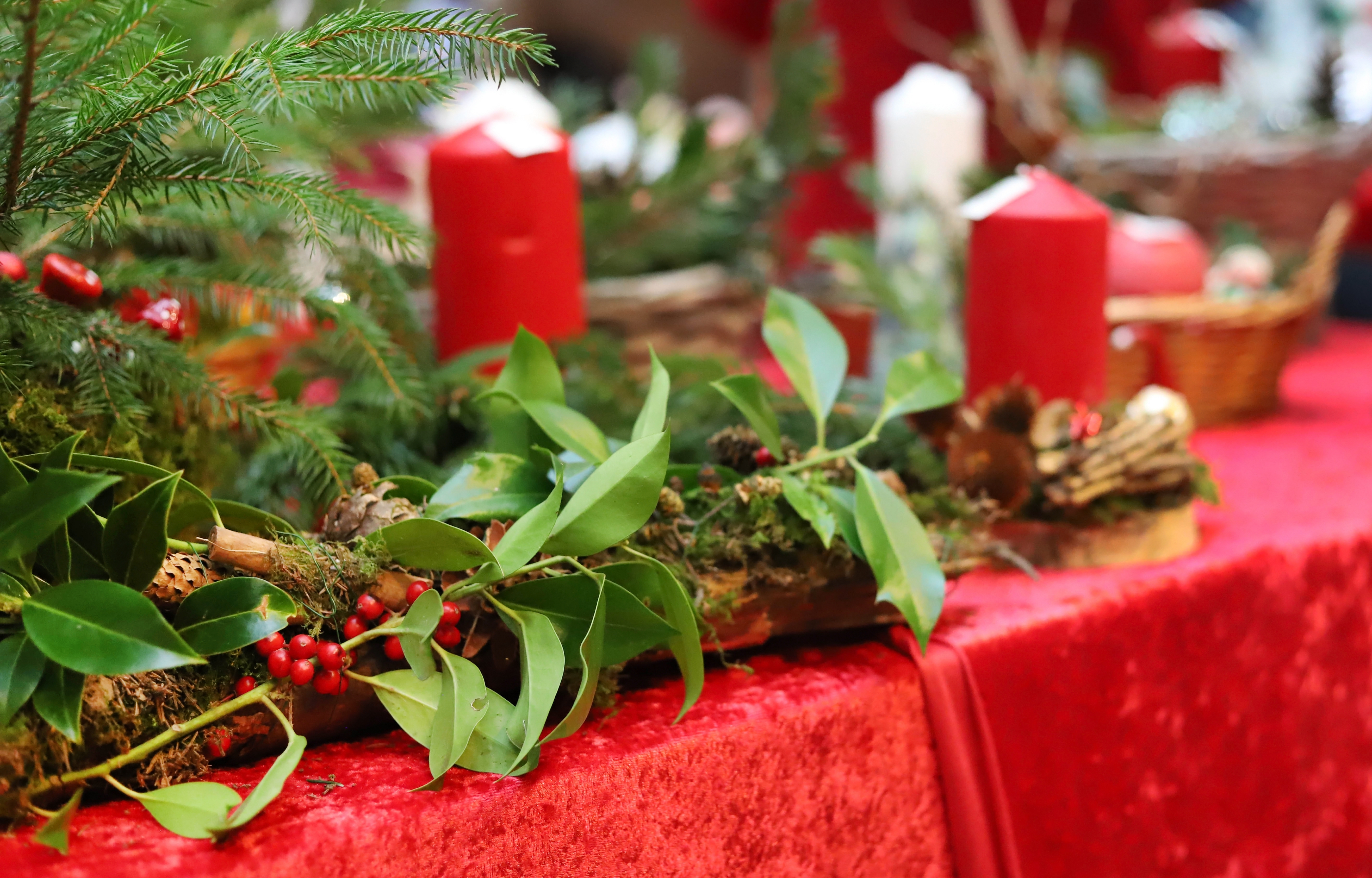Hyggelig dansk julemarked stemning med røde lys, naturlige grønne grene og bær på rustikt træfad