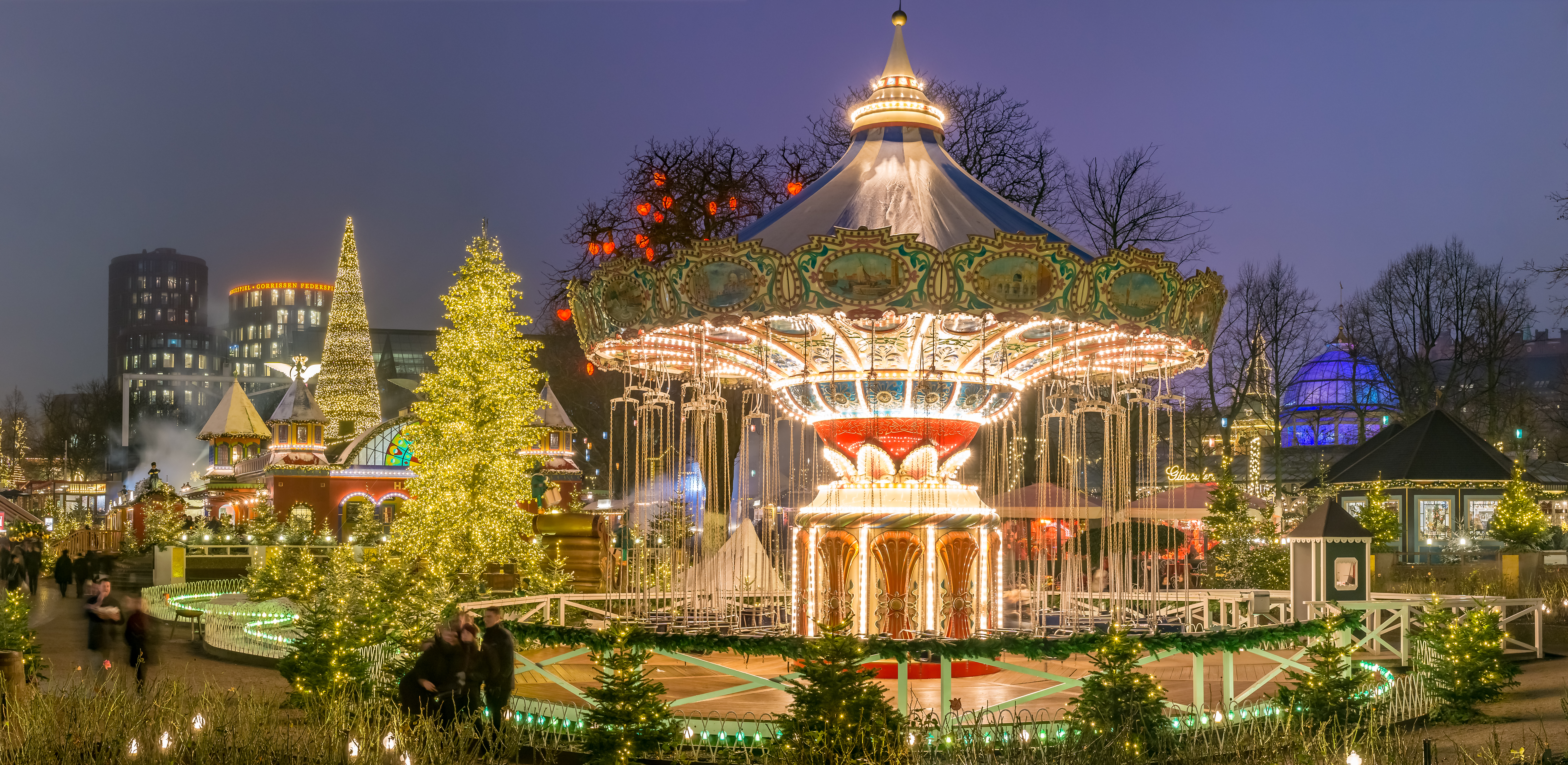 Magisk karusel med julelys og dekorationer på Tivoli i København under blå aftenhimmel