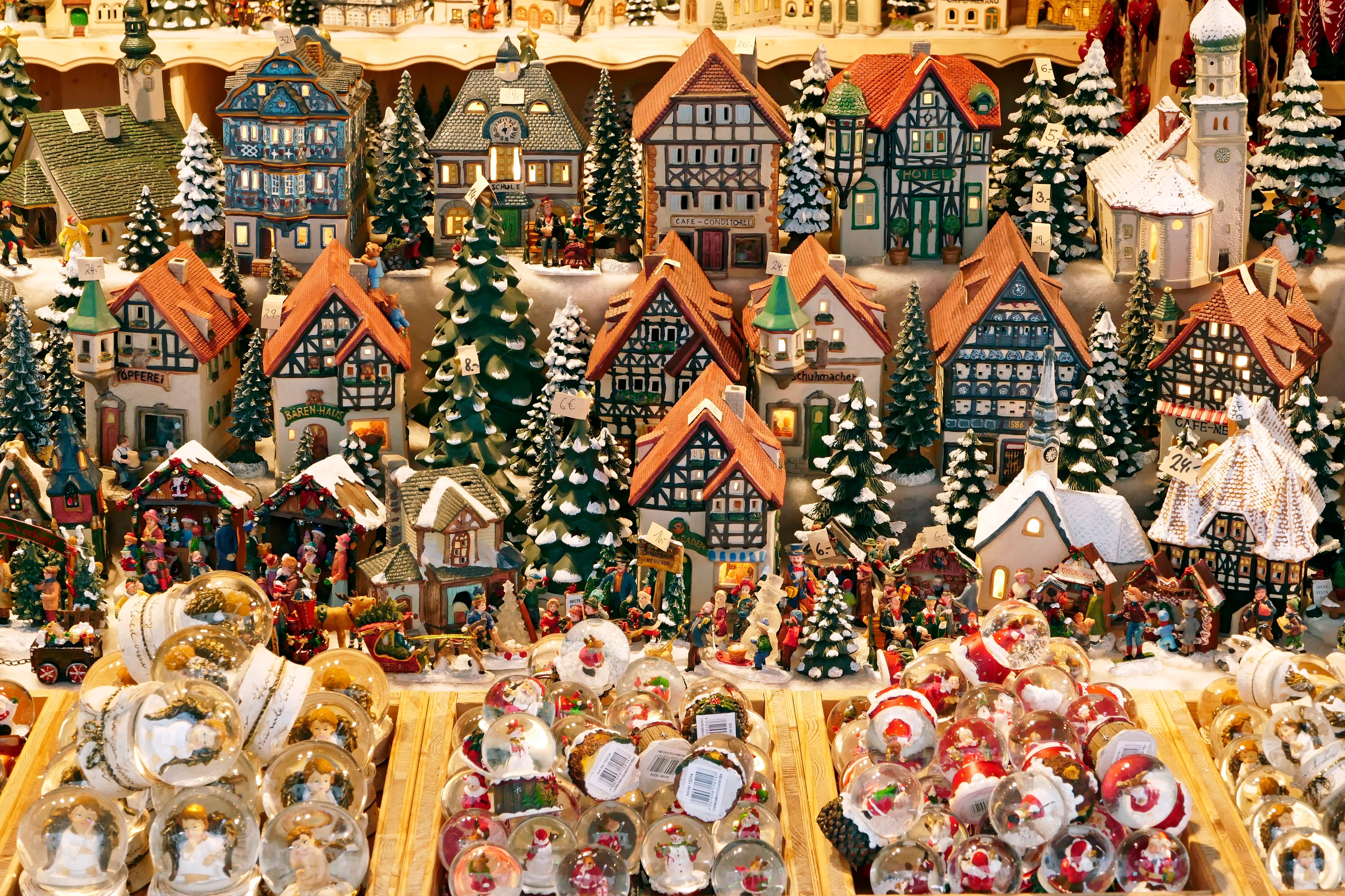 Hyggelig julemarkedsstand i Salzburg med farverige miniaturebyhuse, snedækkede træer og dekorative snekugler på Residenzplatz