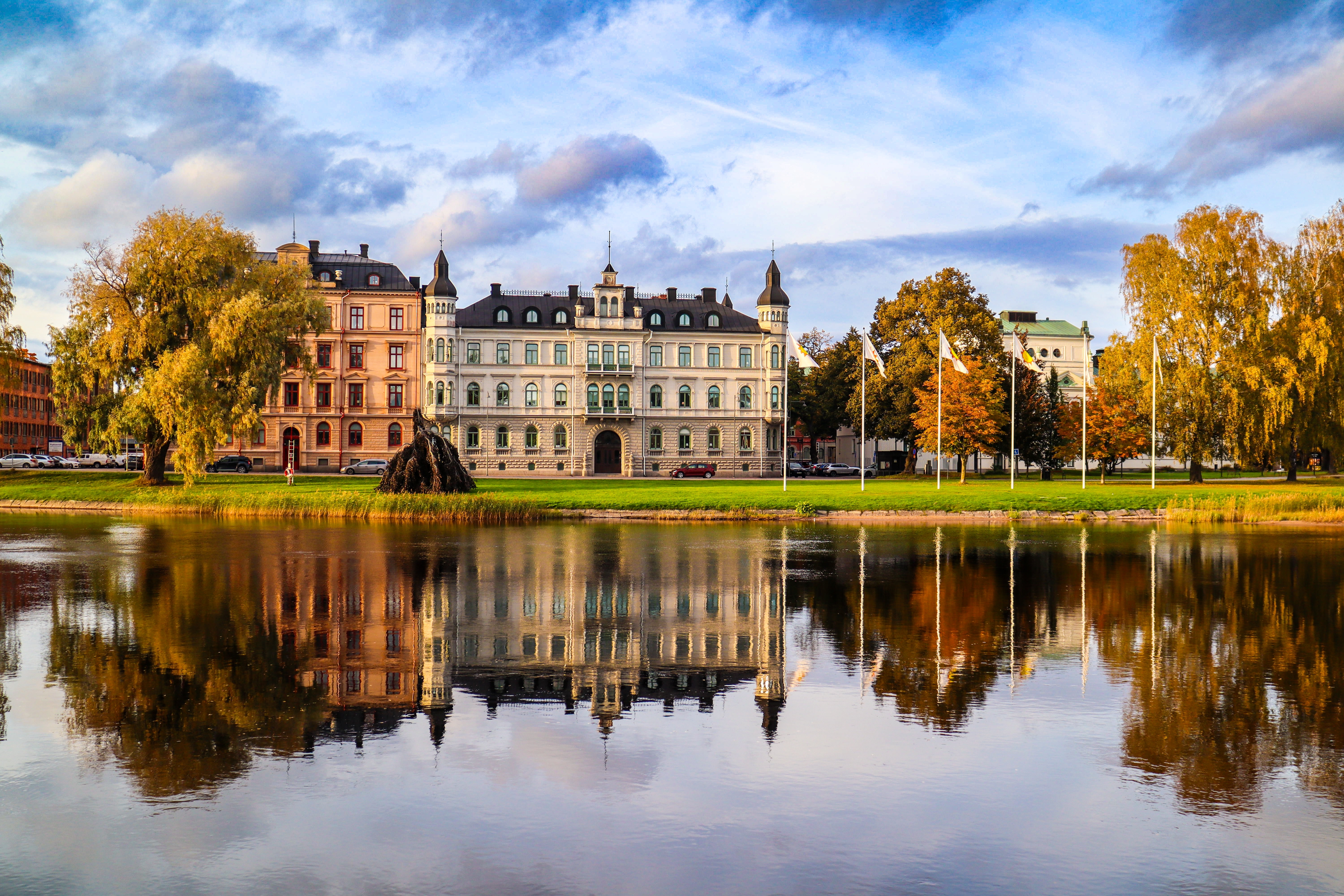 Karlstad i Sverige med klassiske bygninger spejlet i roligt flodvand omgivet af gyldne efterårstræer