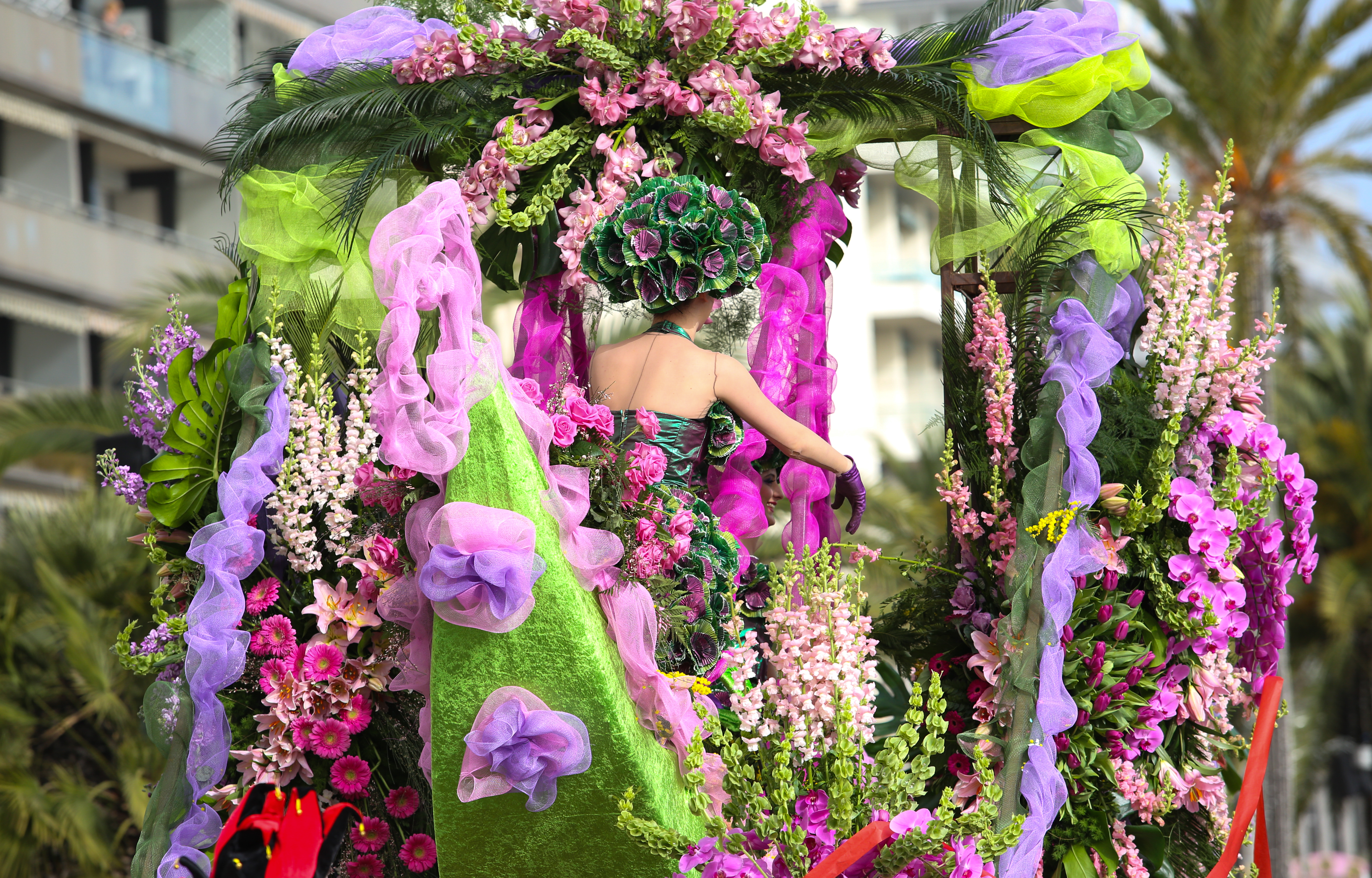 Farverig karnevalsvogn pyntet med lyserøde og lilla blomster ved Nice Karnevalet på den franske Riviera