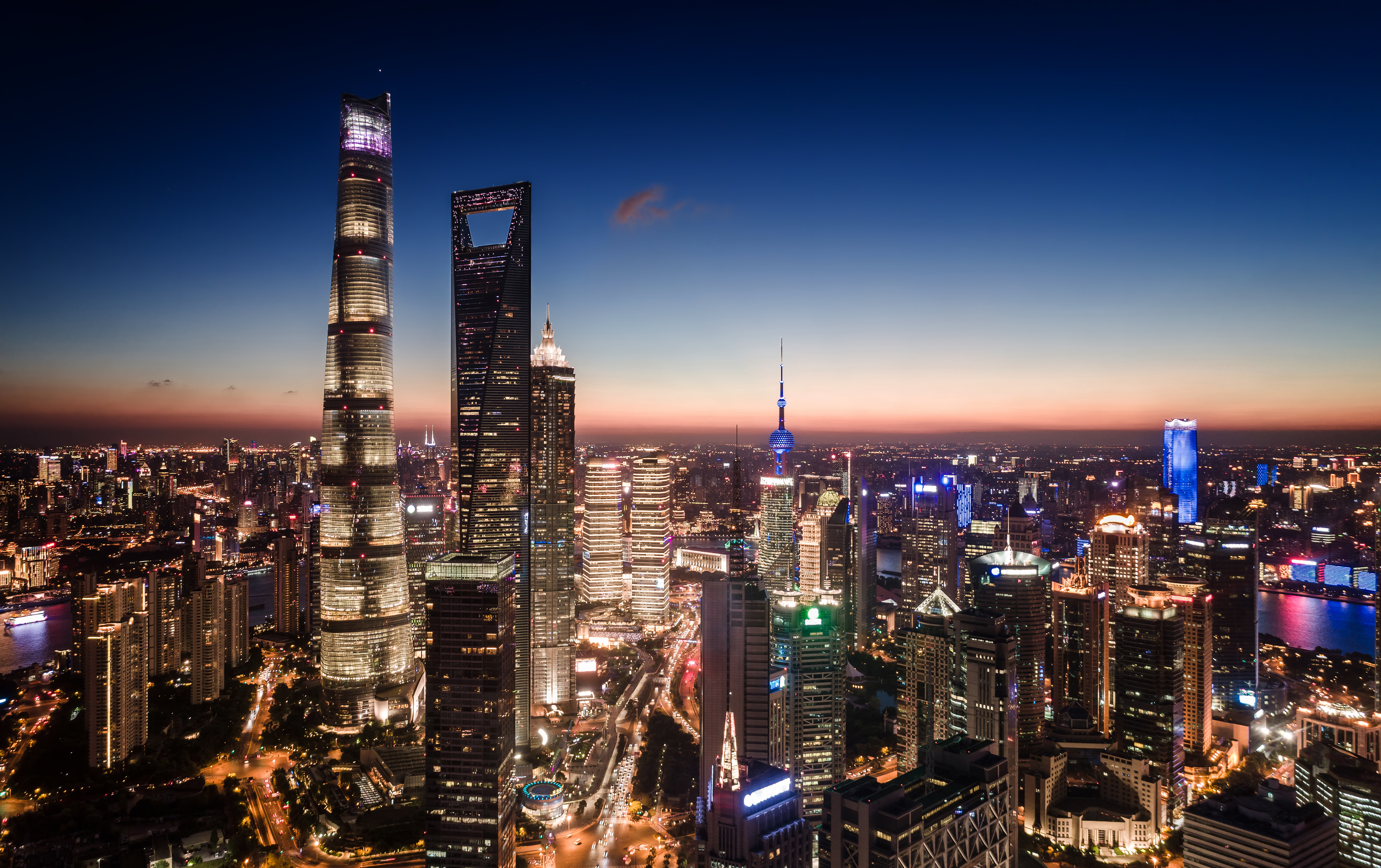 Imponerende natbillede af Shanghais moderne skyline i Pudong med lysende skyskrabere og travle bygader i Kinas største by