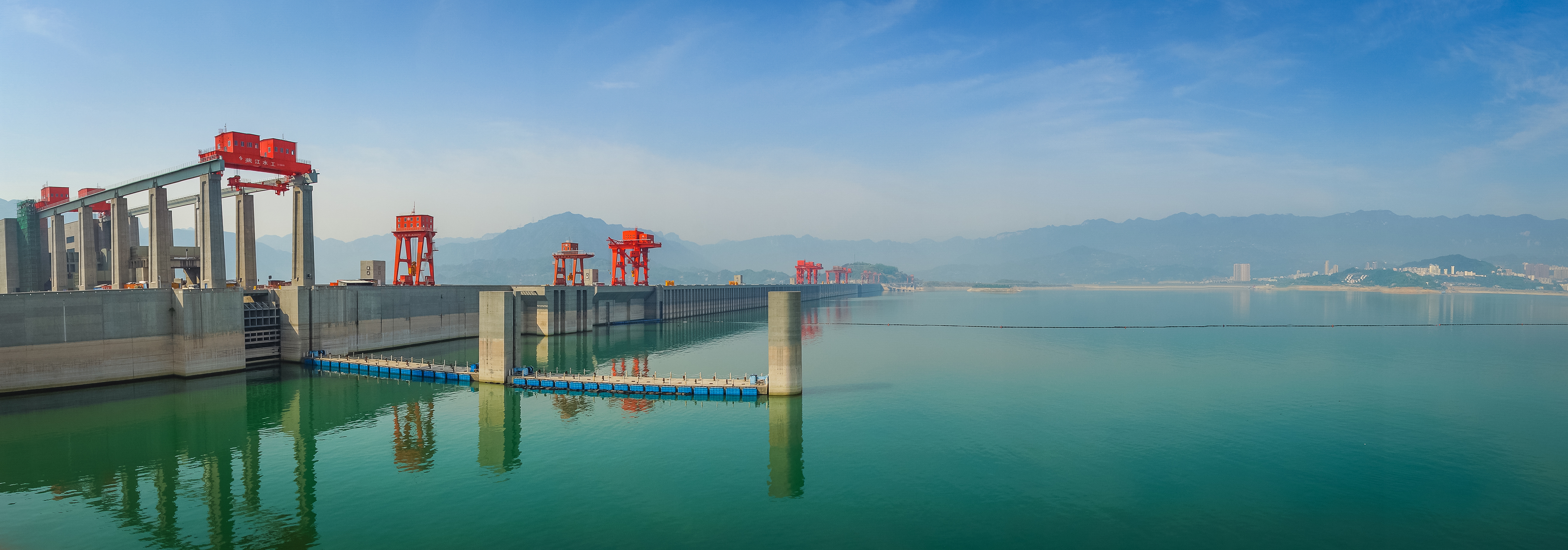 Panoramabillede af Tre Kløfters Dæmning ved Yangtze-floden i Kina med røde industrikraner og turkist vand