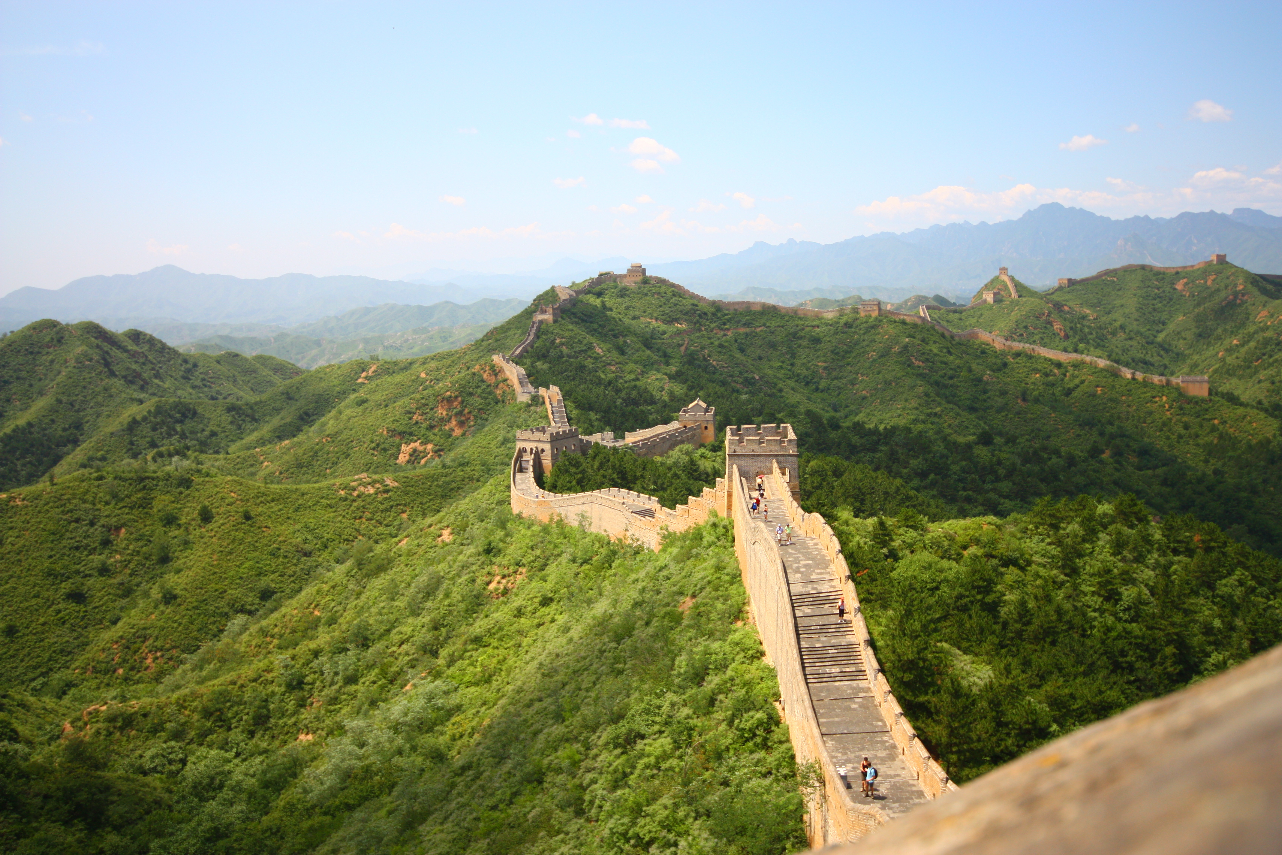 Den Kinesiske Mur gennem frodigt grønt landskab og bjerge i Kina