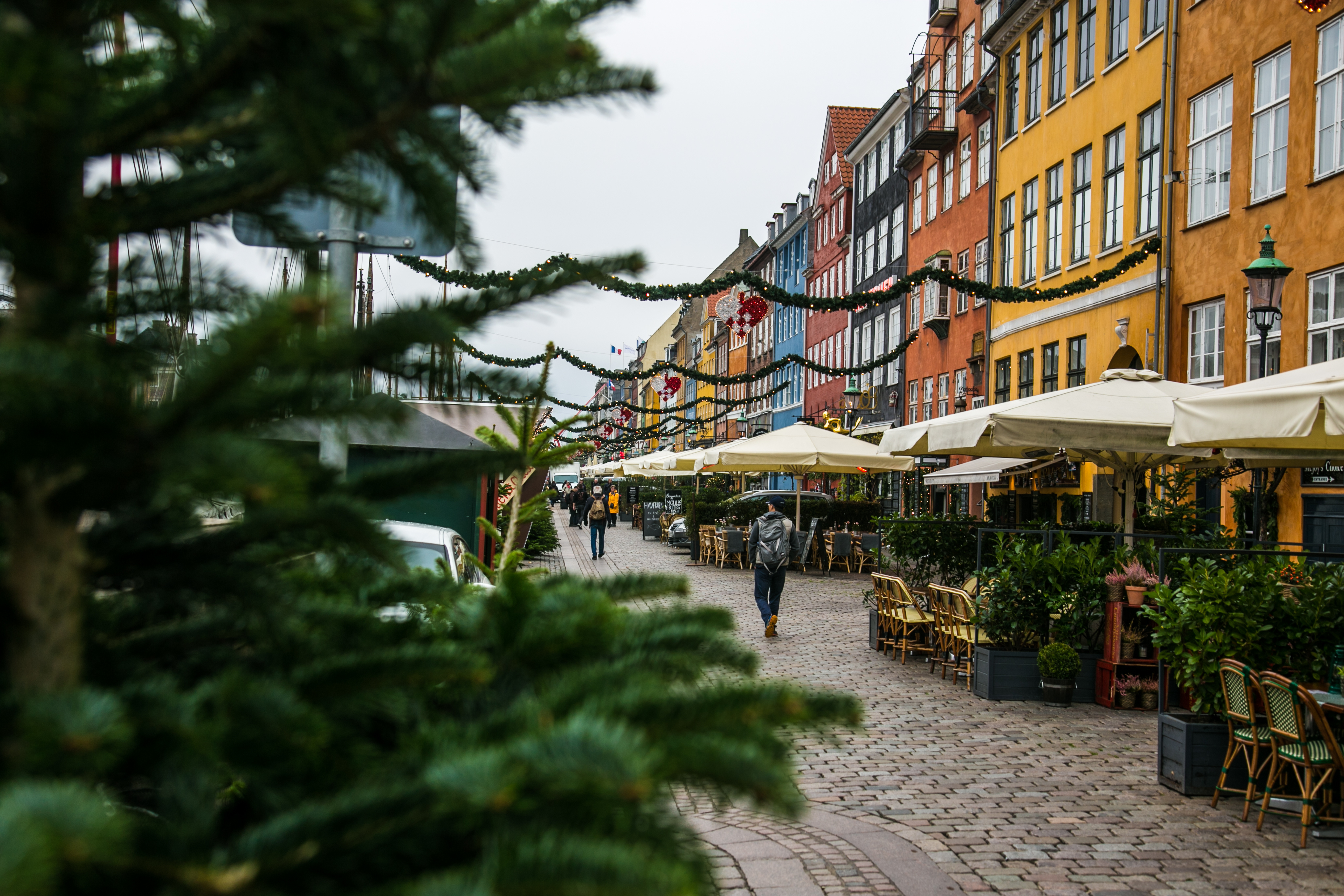 Vinterstemt Nyhavn i København med juledekoration, farverige bygninger og hyggelige caféer langs den brolagte gade