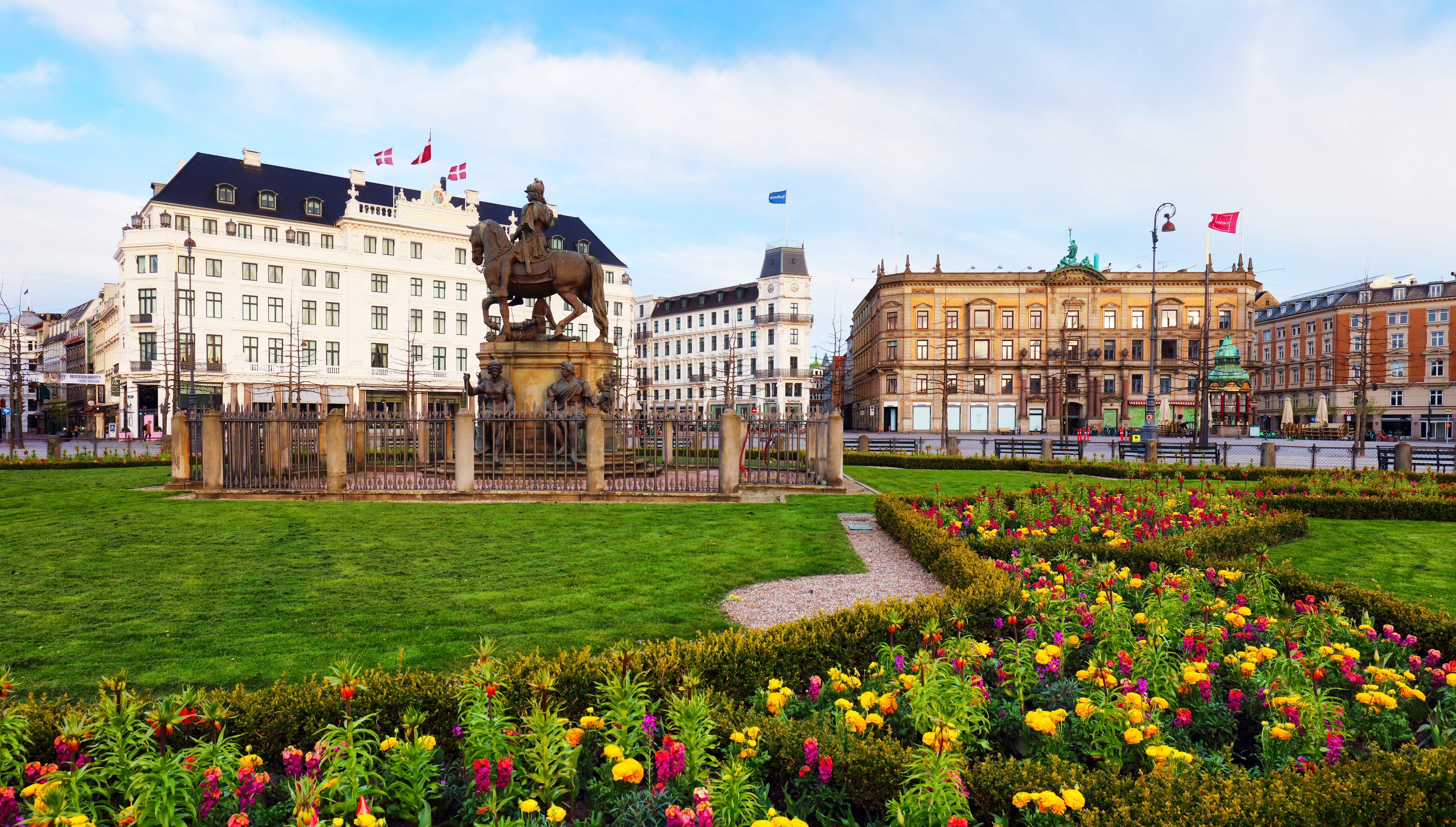 Historisk Kongens Nytorv i København med smukke blomsterhaver og rytterstatue omgivet af klassisk arkitektur