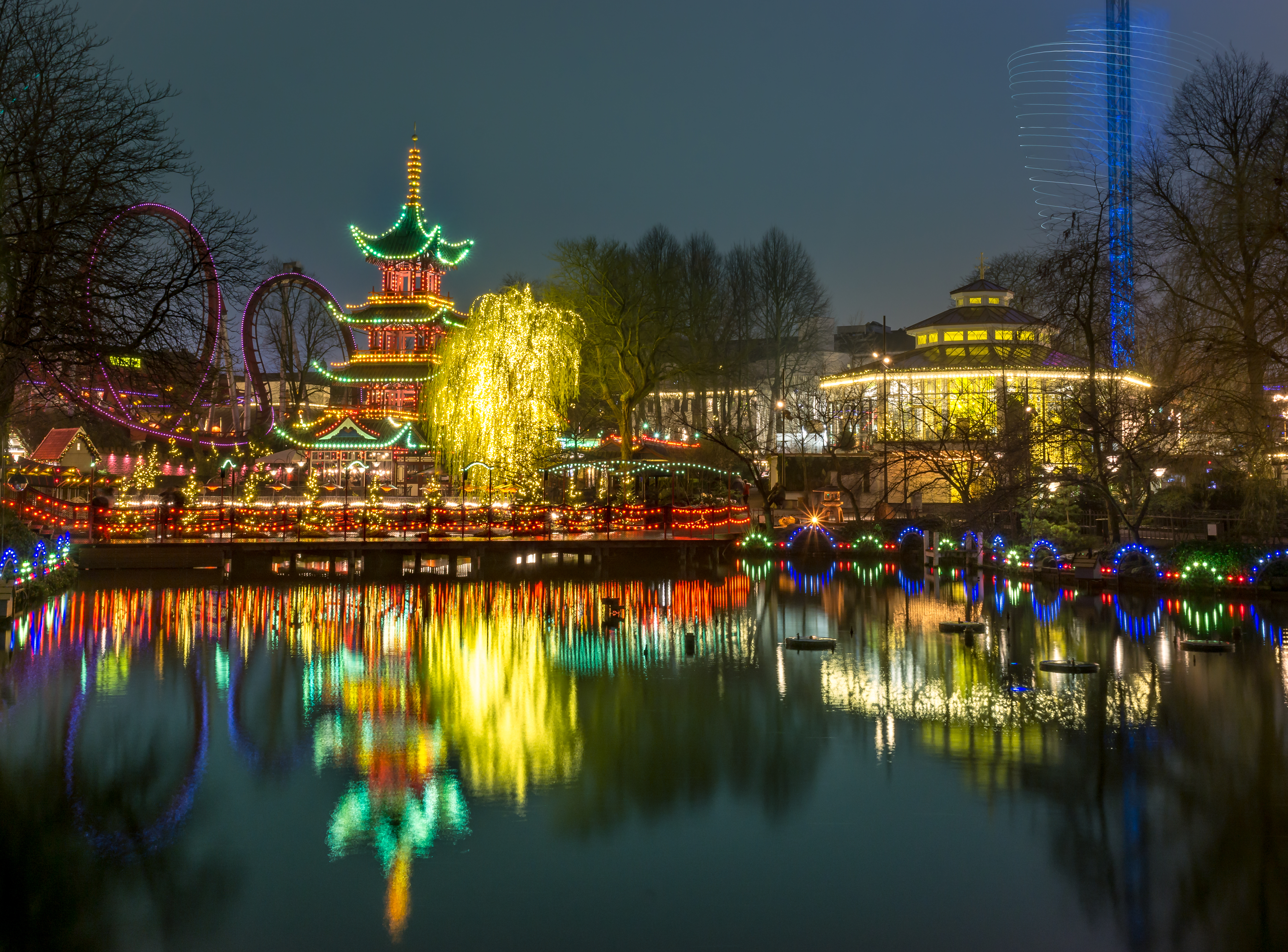 Romantisk aftenbelysning af kinesisk pagoda og forlystelsespark med spejling i vandet på Tivoli