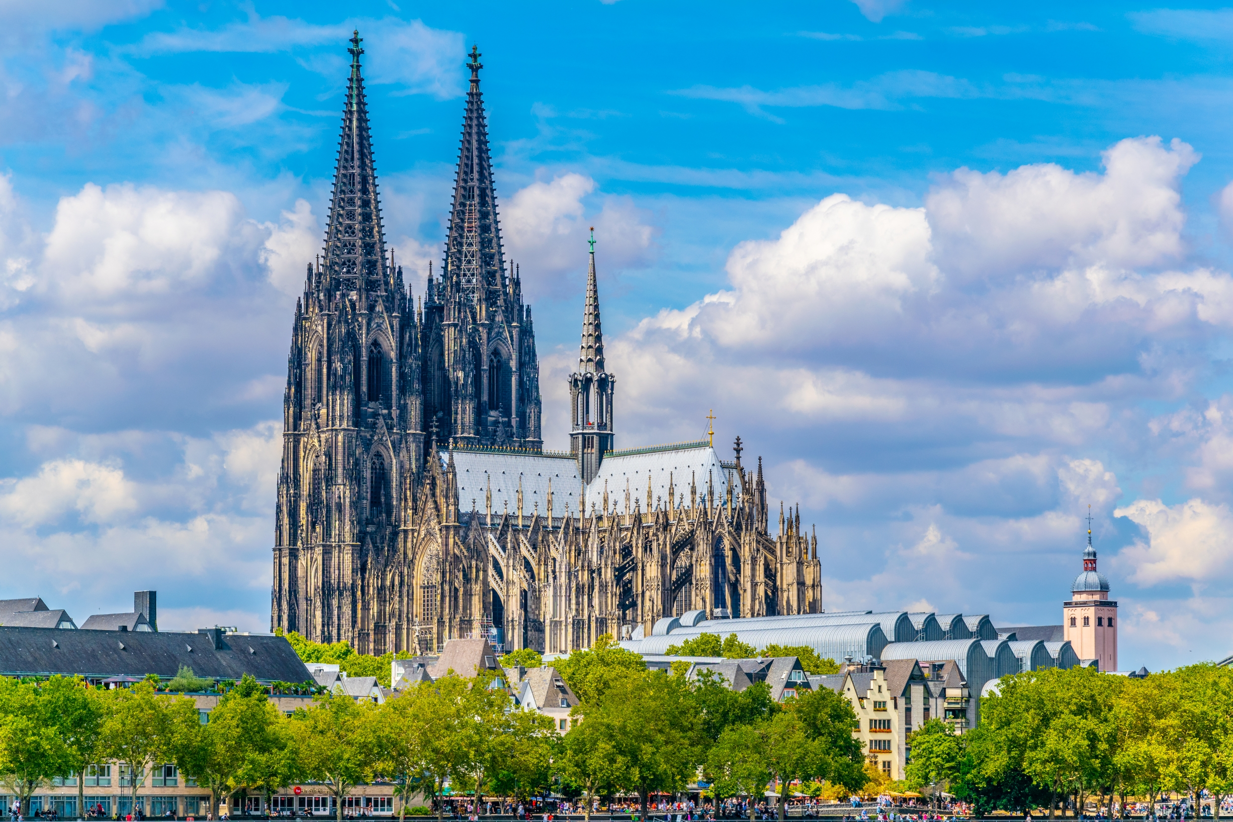 Köln Domkirkes imponerende gotiske facade med to høje spir fotograferet fra Rhinen på en skyfri sommerdag