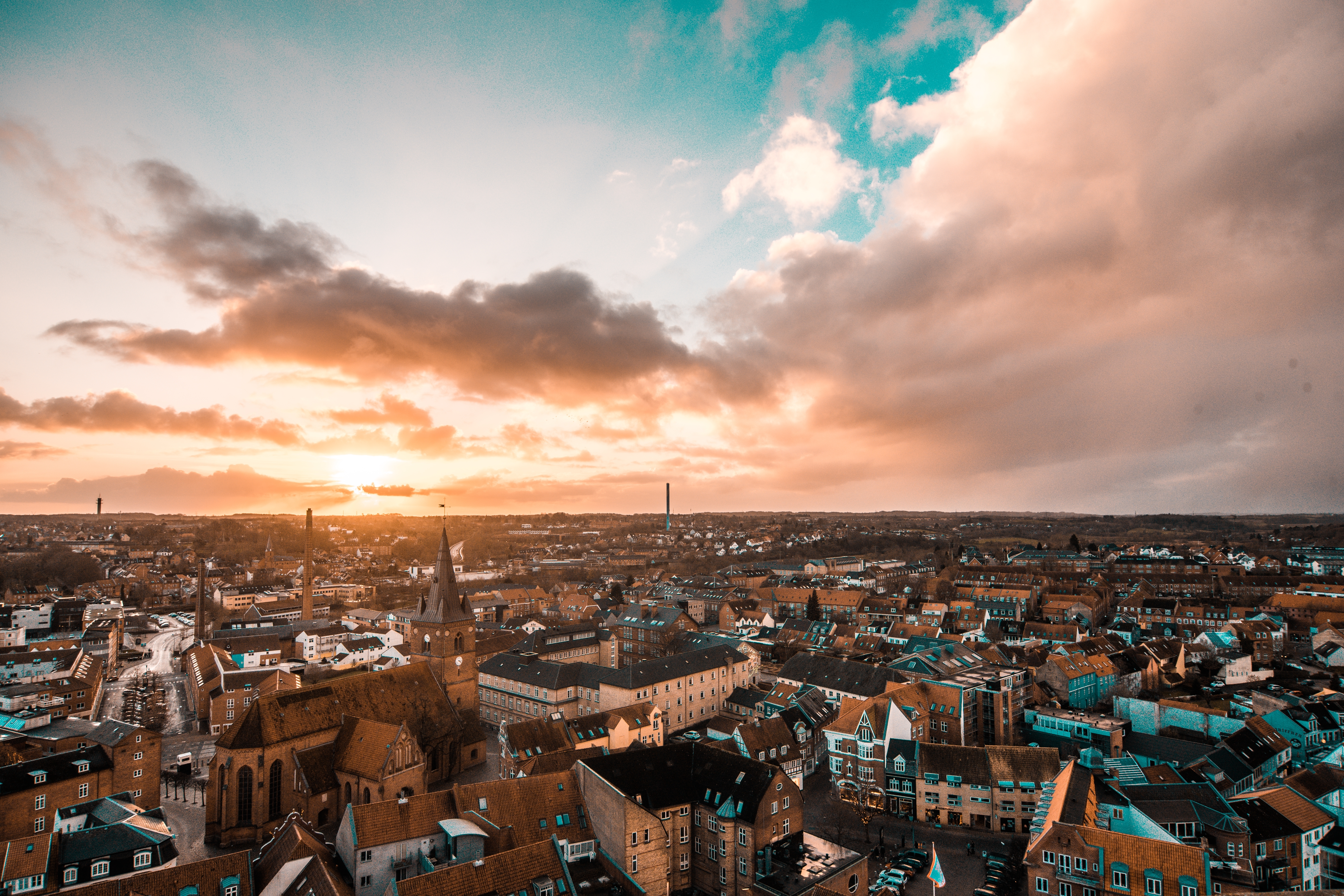 Stemningsfuldt luftfoto over Kolding by i Danmark med gyldent solnedgangslys og smukke kirketårne