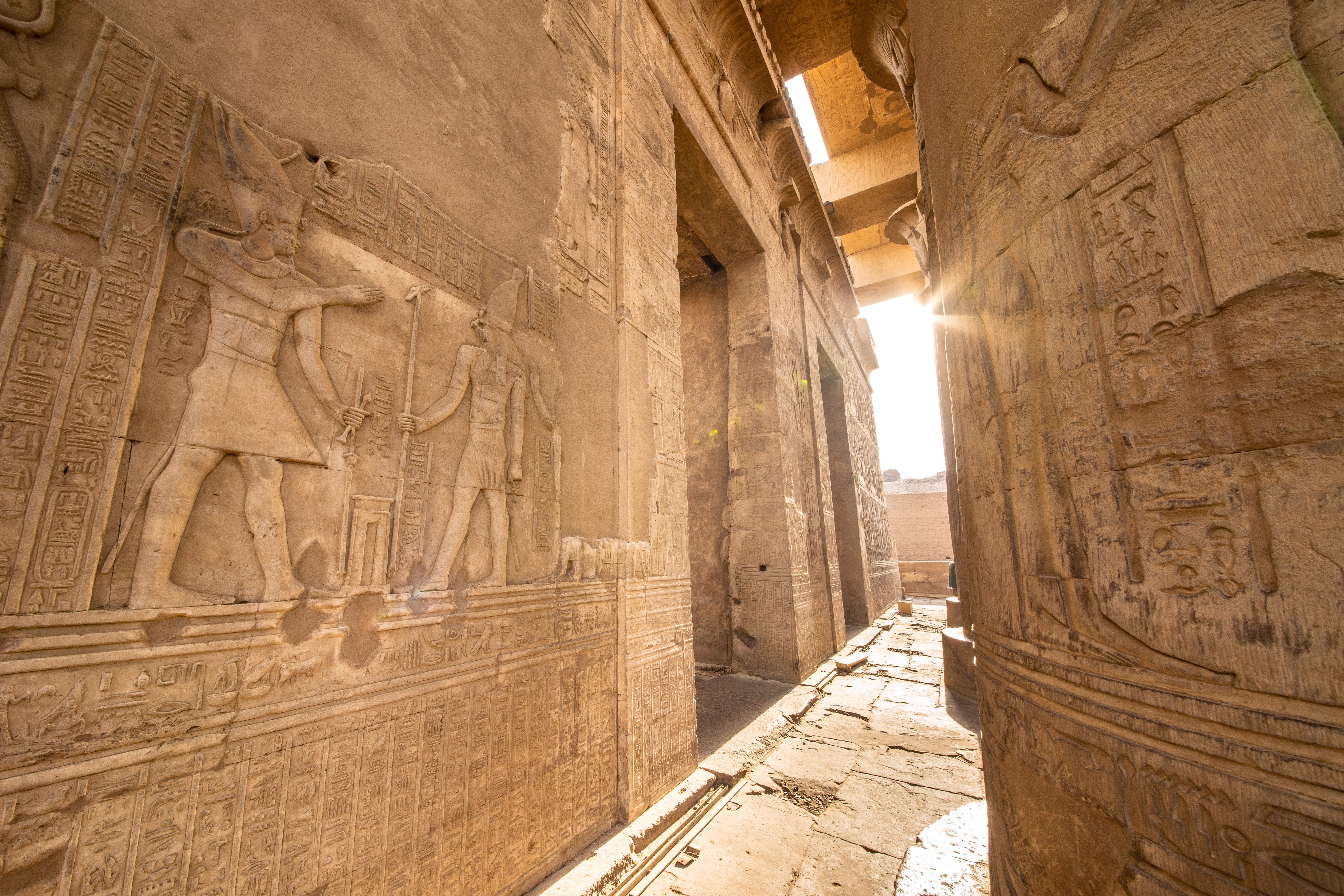 Mystisk korridor med detaljerede hieroglyffer og reliefskulpturer i Kom Ombo templet i Egypten med smukt indfaldende sollys