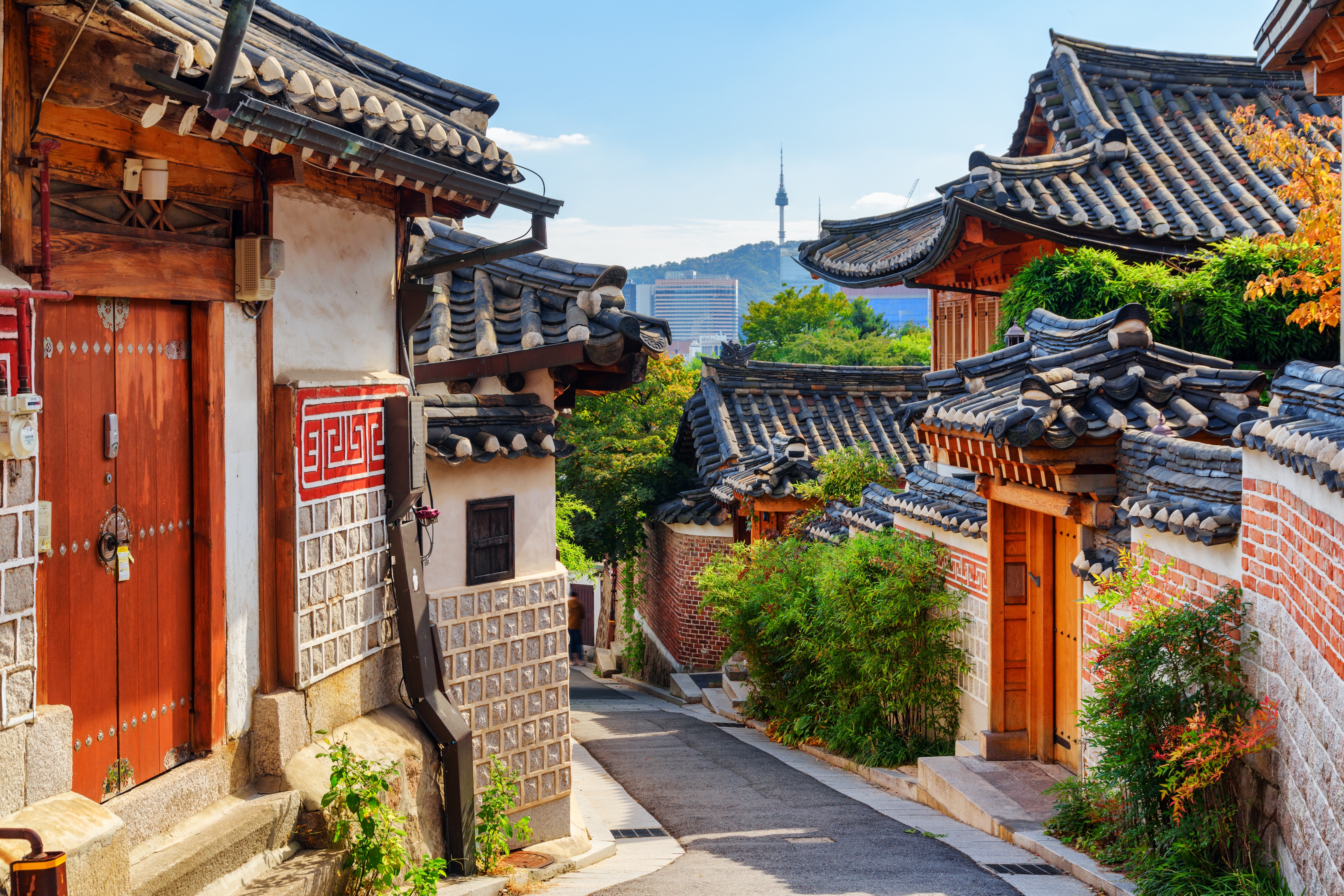 Autentisk koreansk arkitektur i Bukchon Hanok landsbyen med karakteristiske røde tage og Seoultårnet på Namsan-bjerget i baggrunden