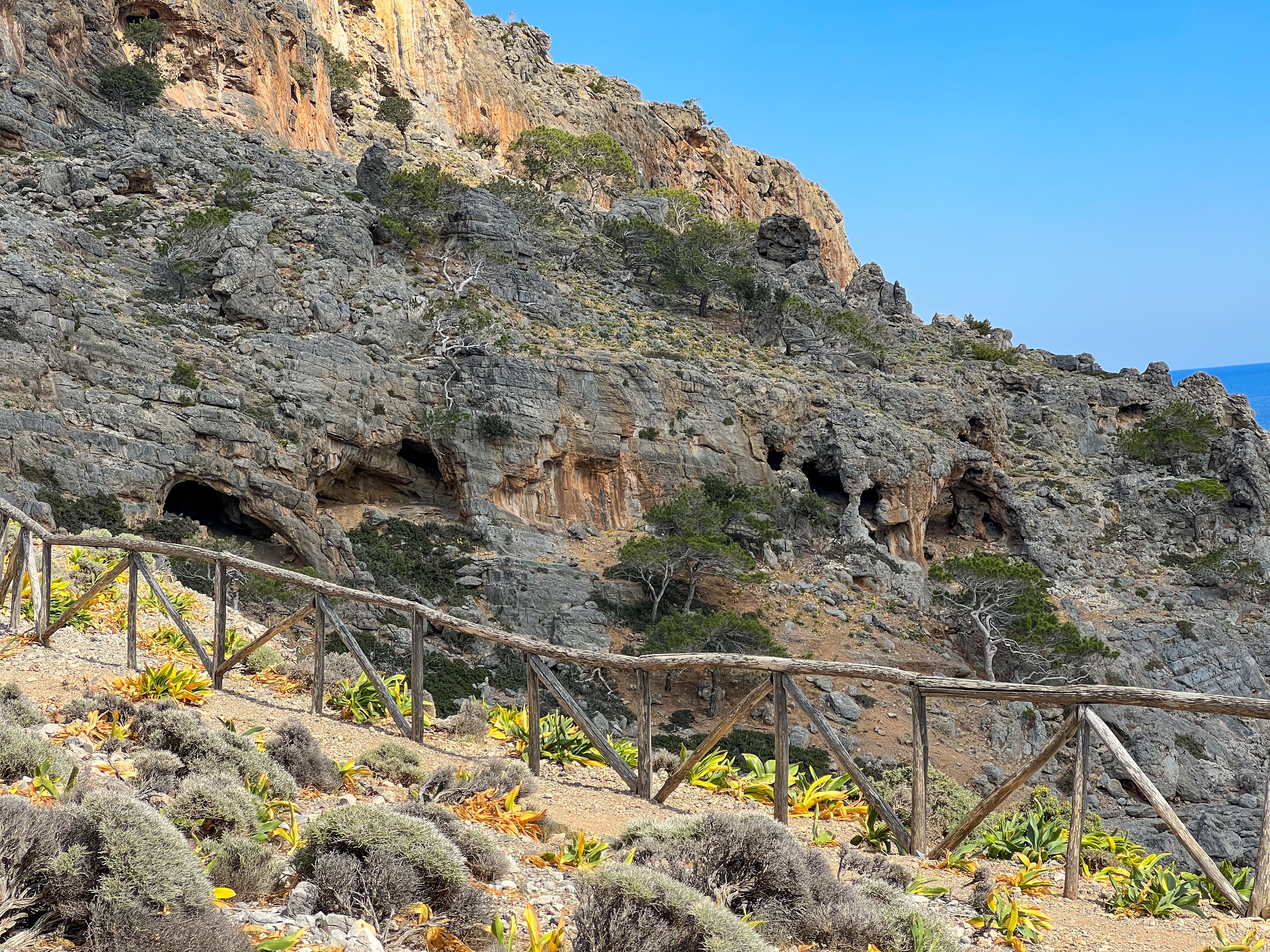 Uberørt natur med markante klippeskrænter og naturlige huler ved Agios Antonios på den vilde sydkyst af Kreta, set fra en vandreesti med trægelænder