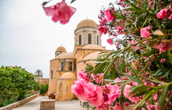 Idyllisk udsigt til det historiske Agia Triada kloster med smukke lyserøde oleanderblomster på Kreta, Grækenland
