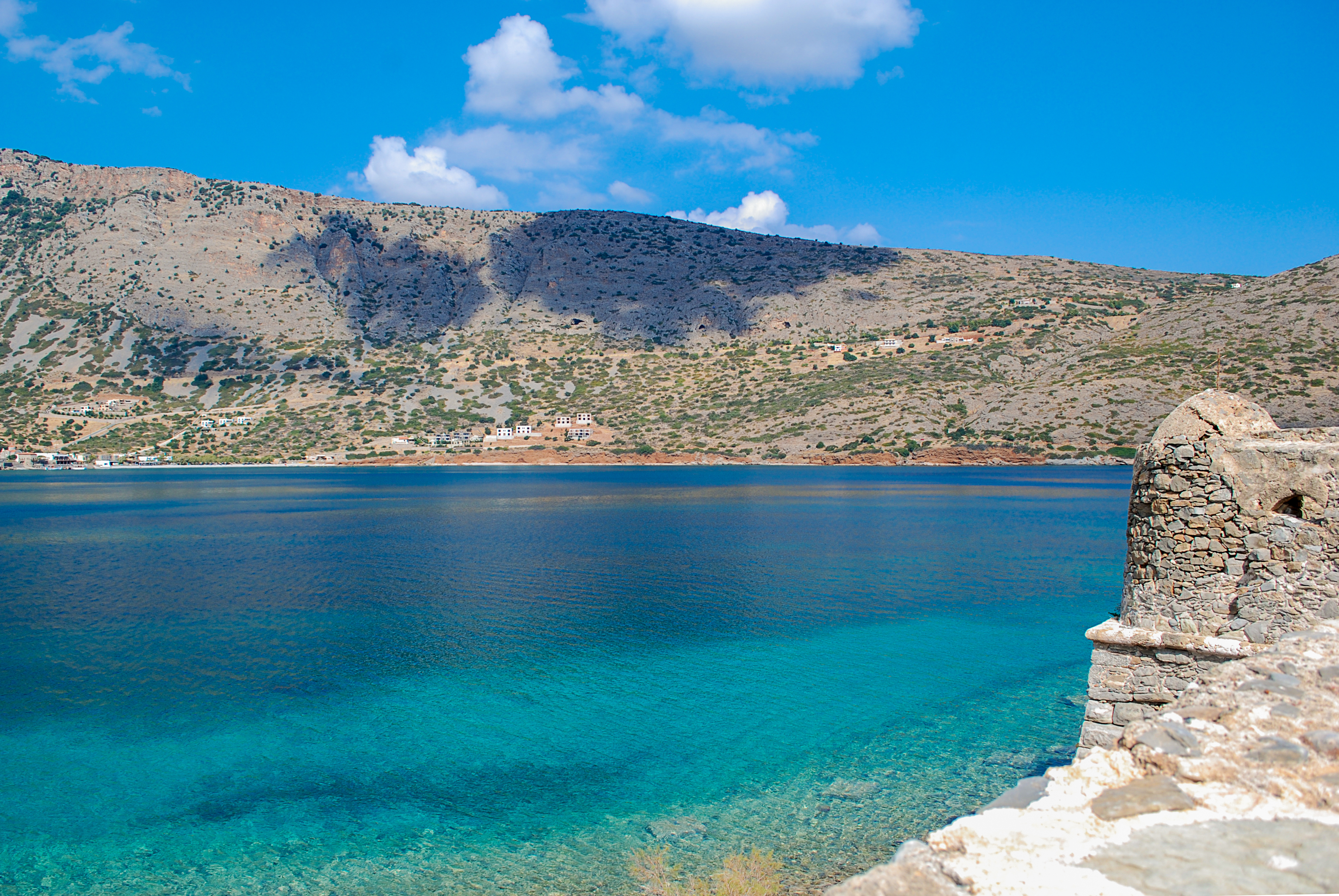 Smuk udsigt over det turkisblå hav ved Spinalonga på Kreta med venetianske fæstningsruiner og bjerglandskab