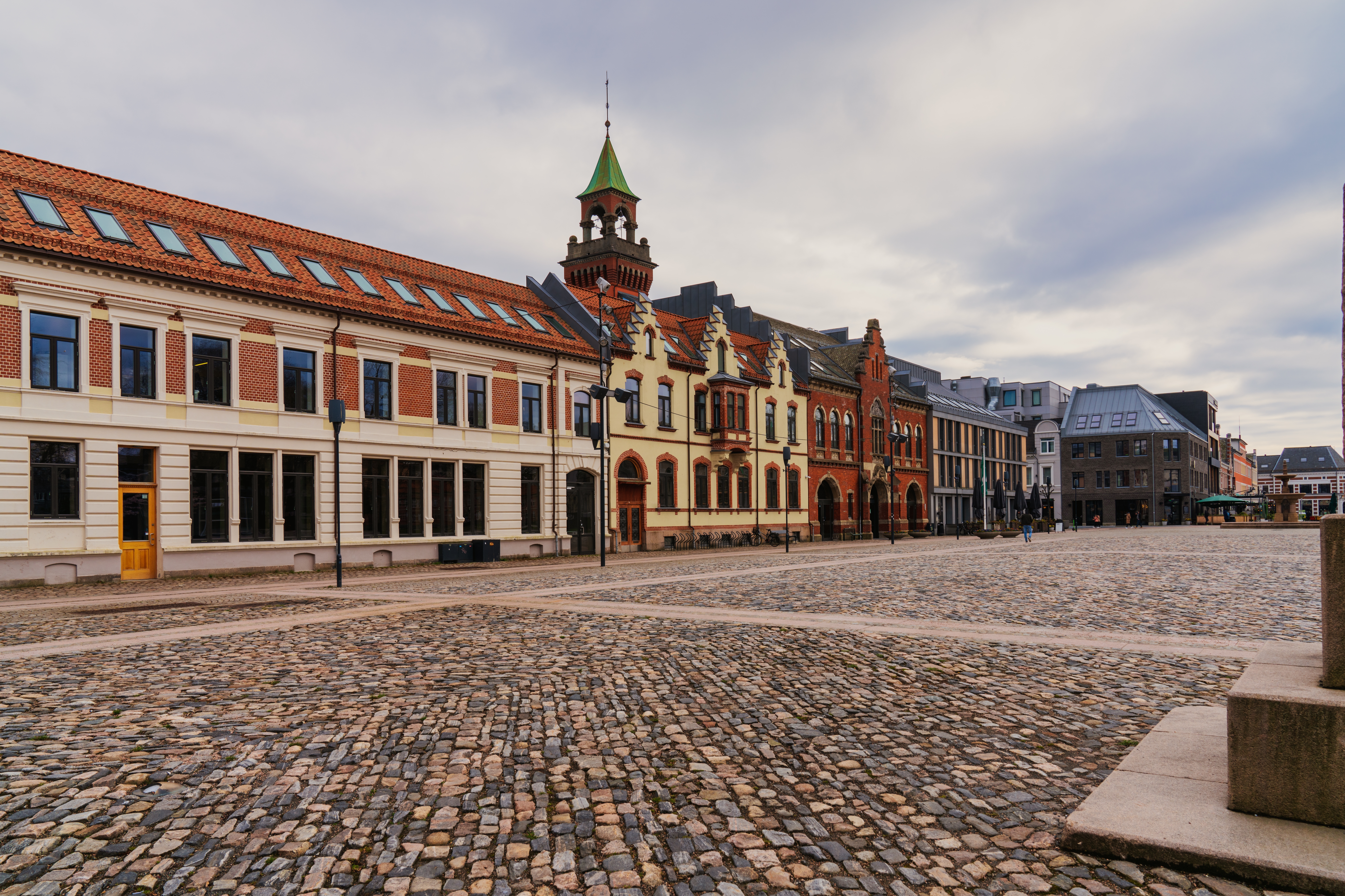 Historisk brolagt torv i Kristiansand med imponerende gamle bygninger og rådhustårn i Agder, Norge