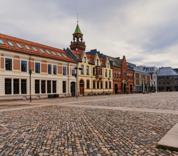 Historisk brolagt torv i Kristiansand med imponerende gamle bygninger og rådhustårn i Agder, Norge