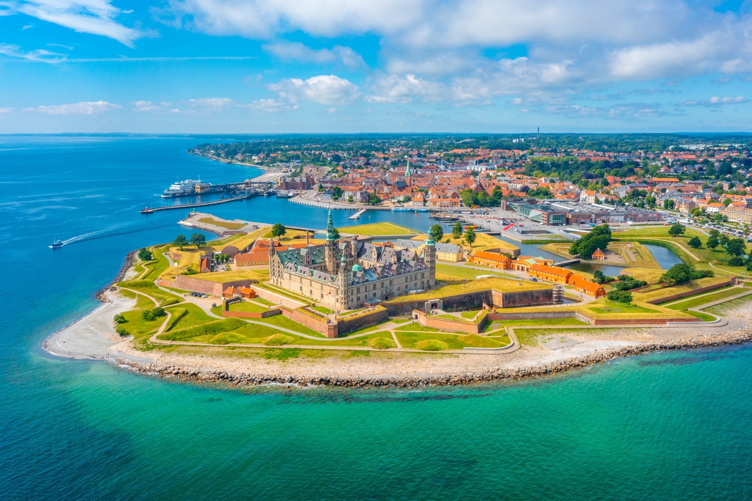 Imponerende fugleperspektiv over Kronborg Slot og fæstningen i Helsingør, Danmark, med det turkise Øresund i forgrunden