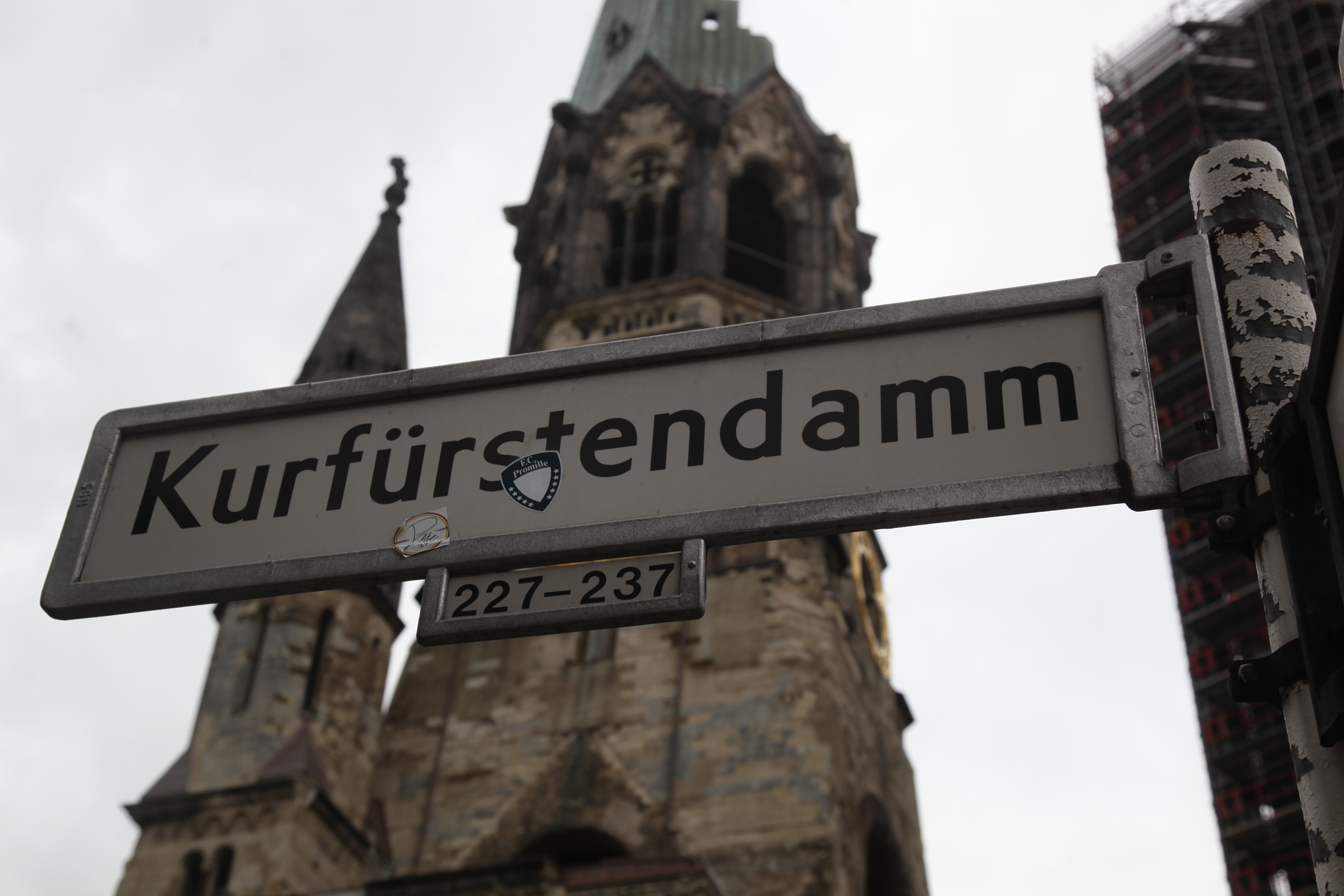 Gadeskilt på Kurfürstendamm i Berlin med Kaiser Wilhelm Gedächtniskirche synlig i baggrunden