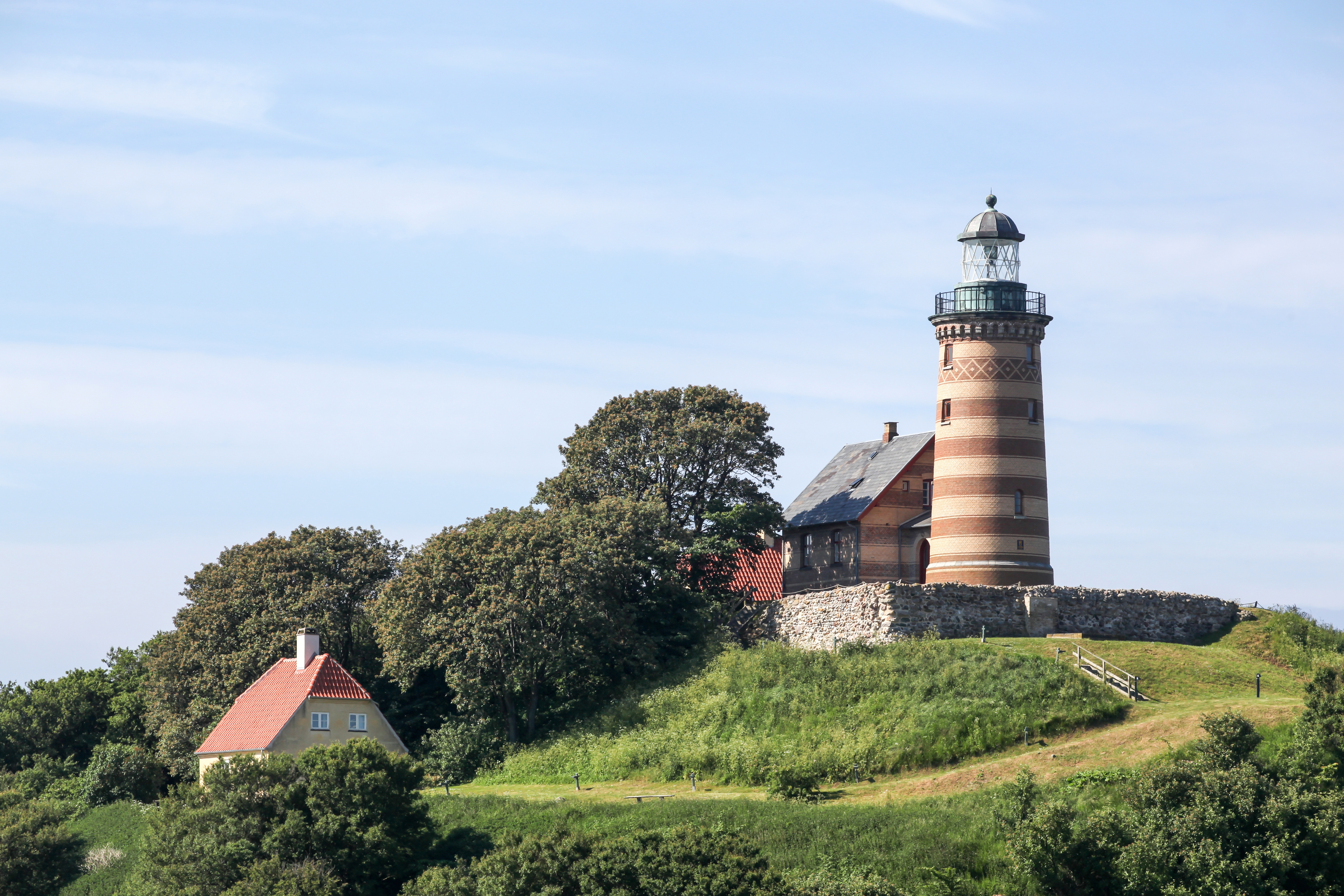 Kystfyrtårn med røde og hvide striber omgivet af traditionelle danske huse med røde tegltagе