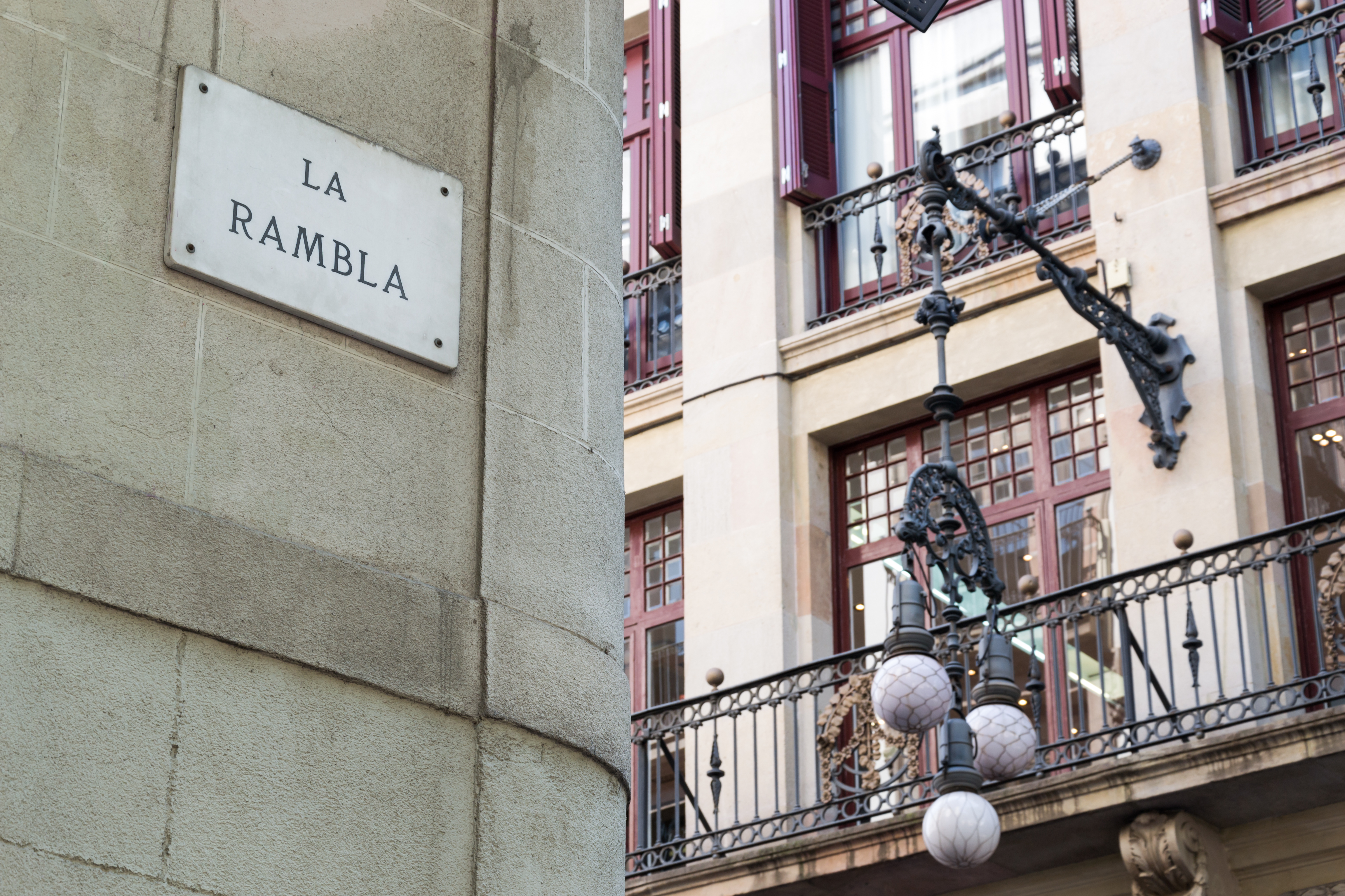 Gadeskilt for La Rambla i Barcelona med smuk antik lygtepæl og historisk bygning i baggrunden