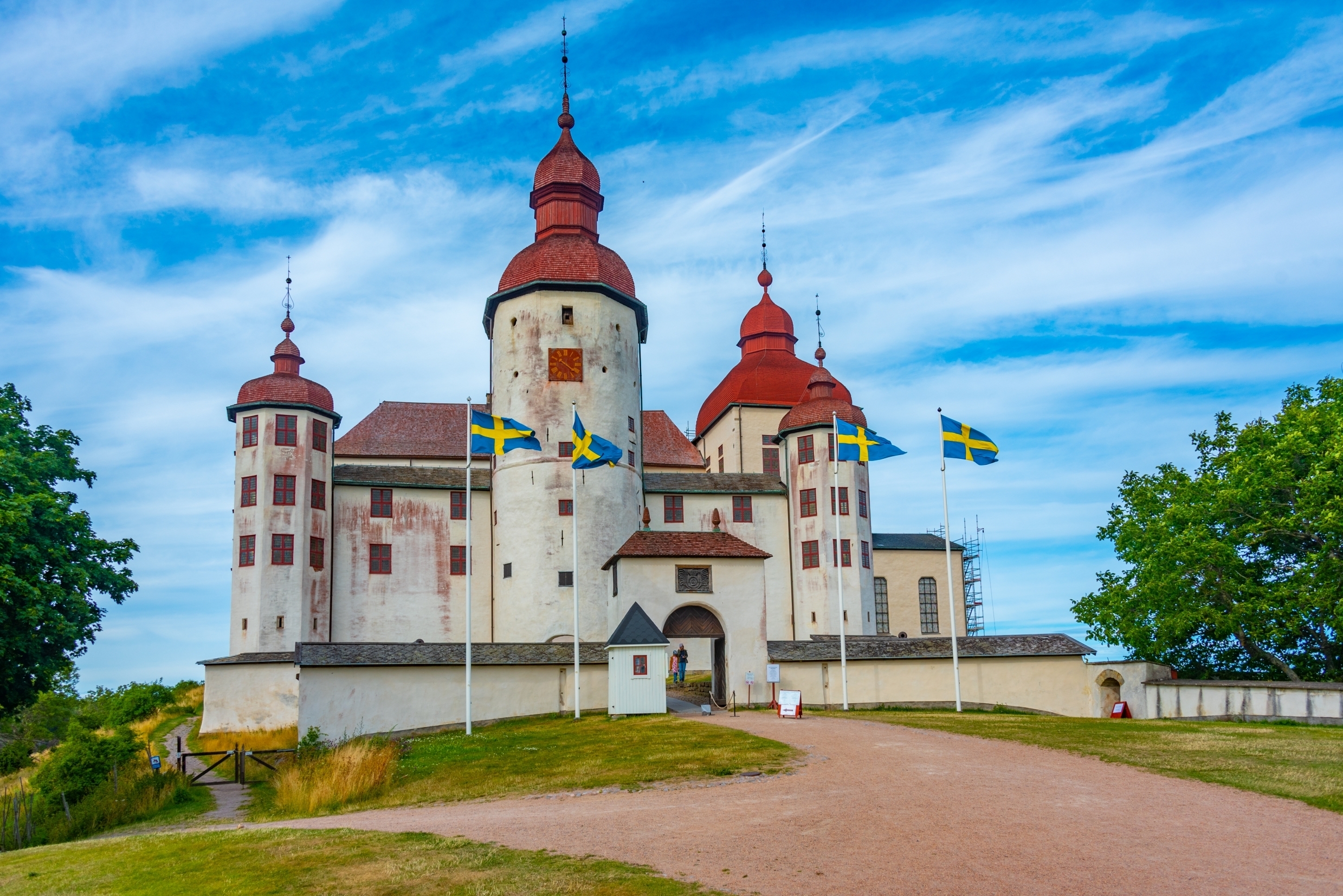 Besøg det smukke Läckö Slot i Sverige - et middelalderligt slot med røde kuppeltårne og svenske flag i det skønne sommervejr