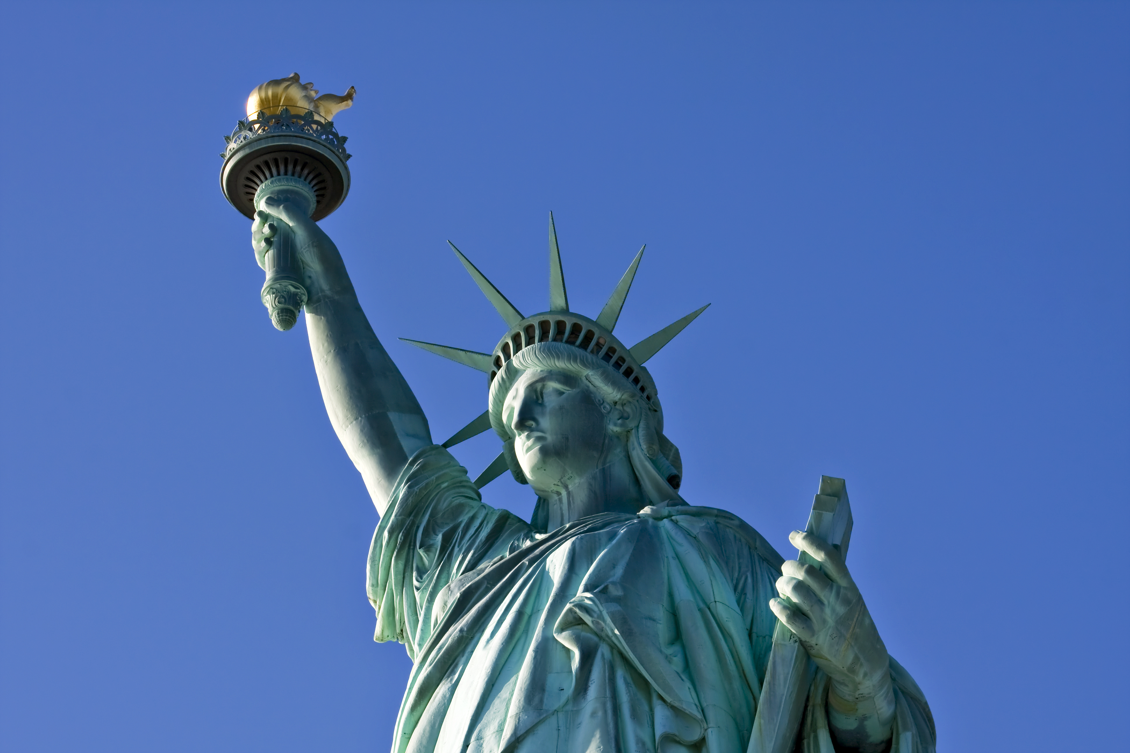 Frihedsstatuen på Liberty Island med krone og fakkel mod blå himmel