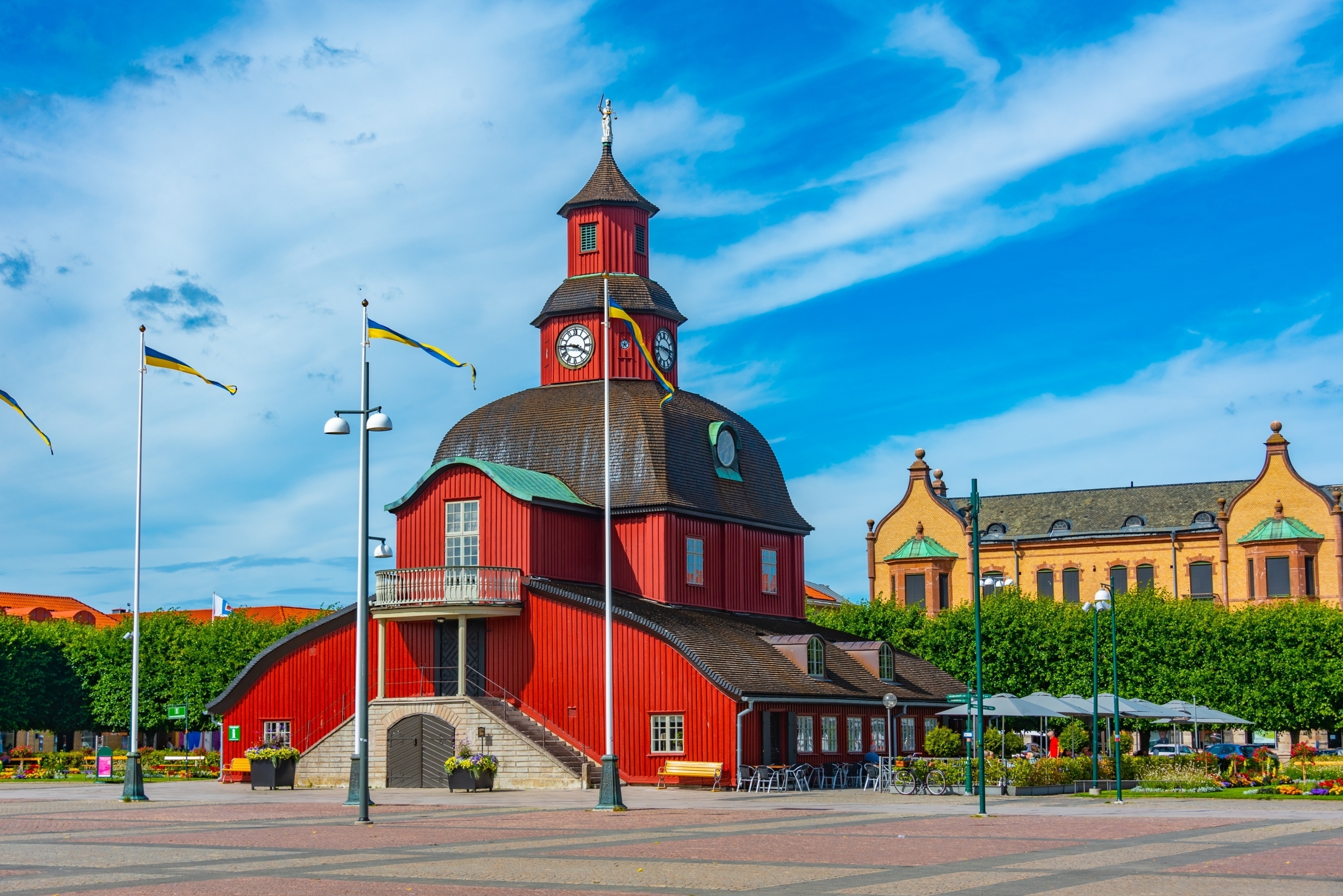 Malerisk rødt trærådhus på torvet i Lidköping, Sverige, med svenske flag og klokketårn på en solrig dag