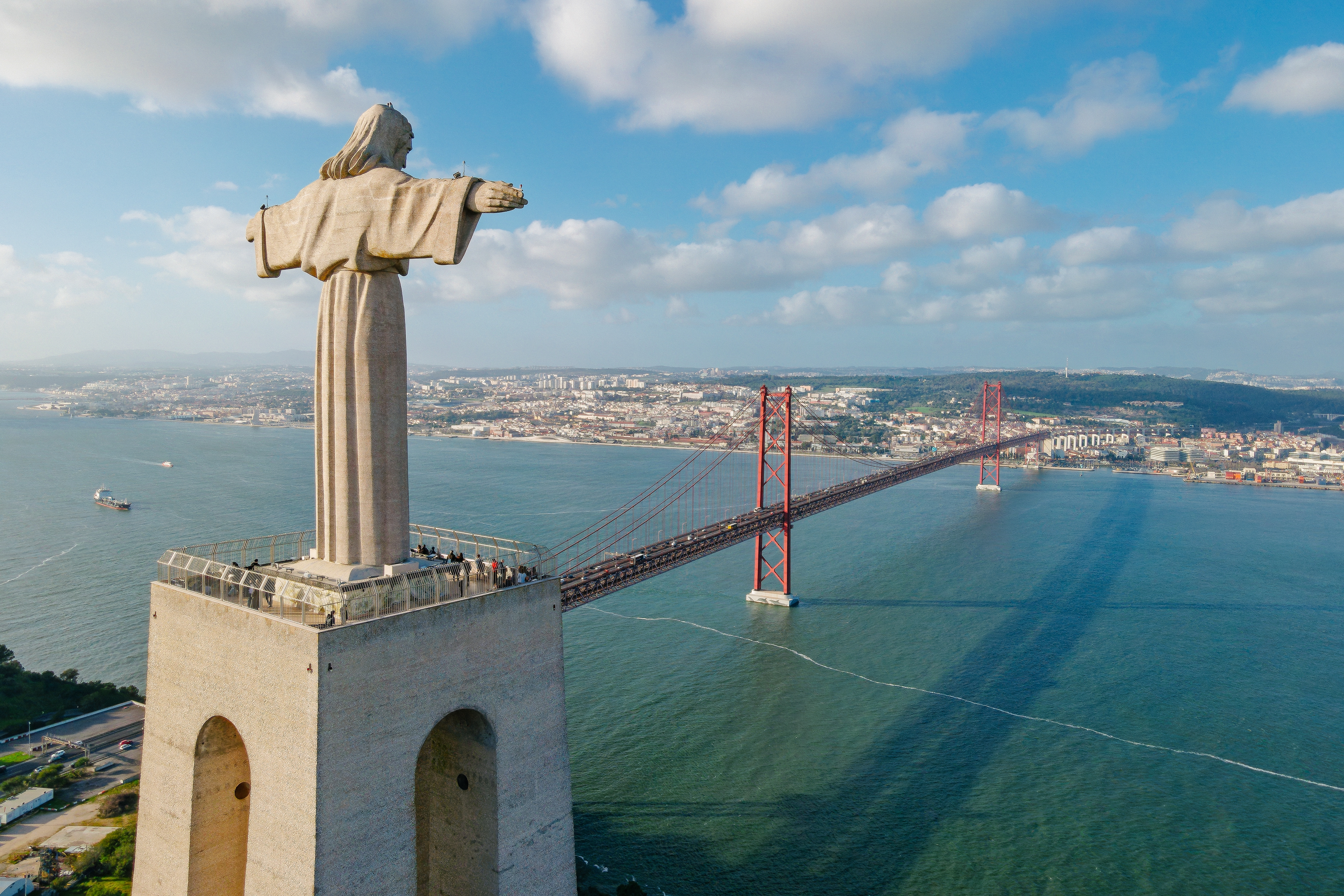 Spektakulær luftudsigt over Cristo Rei-statuen og 25. April-broen over Tejo-floden med Lissabons skyline, Portugal