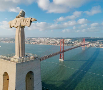 Spektakulær luftudsigt over Cristo Rei-statuen og 25. April-broen over Tejo-floden med Lissabons skyline, Portugal