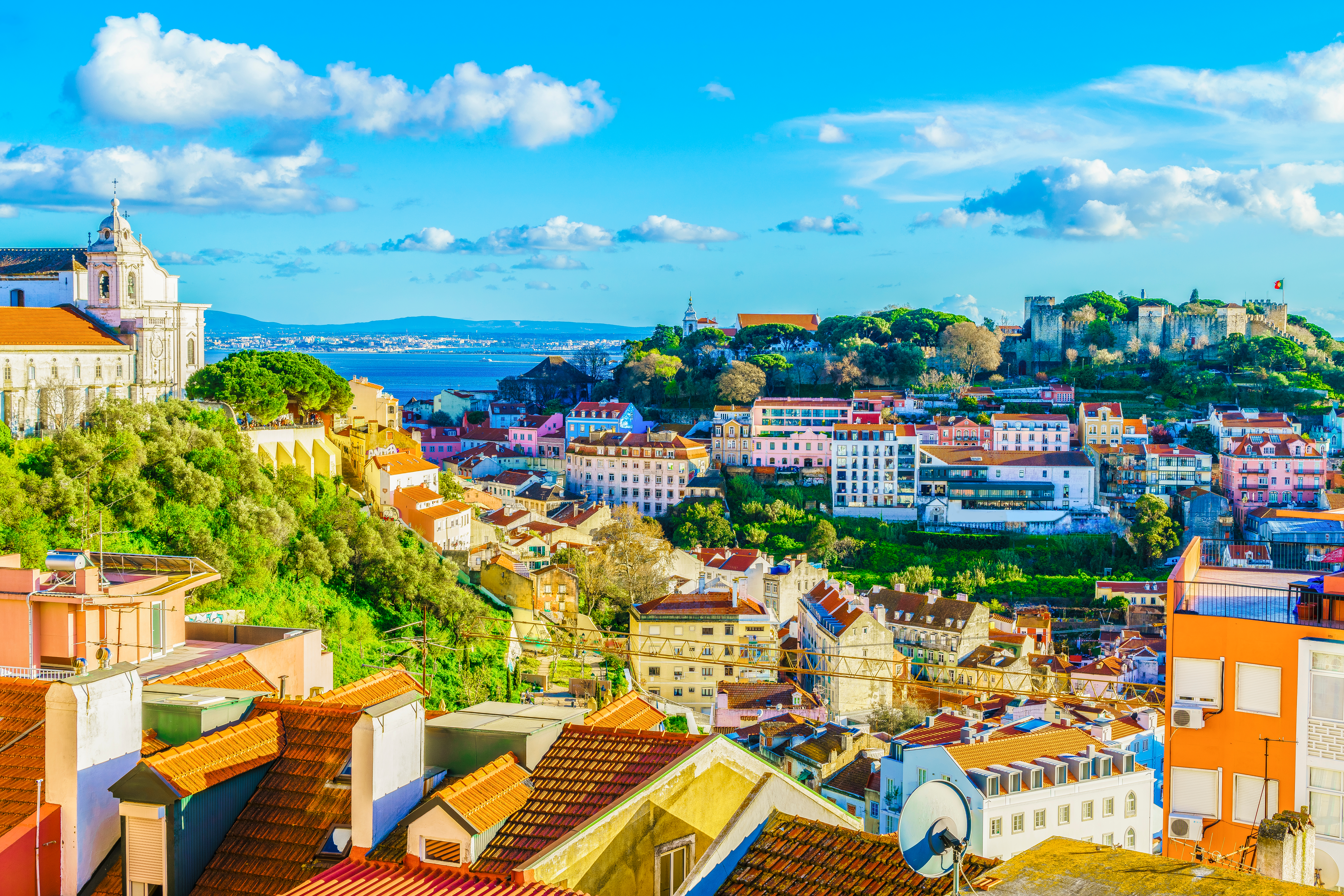 Storslået udsigt over Lissabons ældste kvarter Alfama med dets karakteristiske teglstenstage, traditionelle portugisiske arkitektur og charmerende bygninger, der følger bakkens konturer