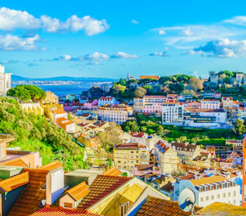Storslået udsigt over Lissabons ældste kvarter Alfama med dets karakteristiske teglstenstage, traditionelle portugisiske arkitektur og charmerende bygninger, der følger bakkens konturer