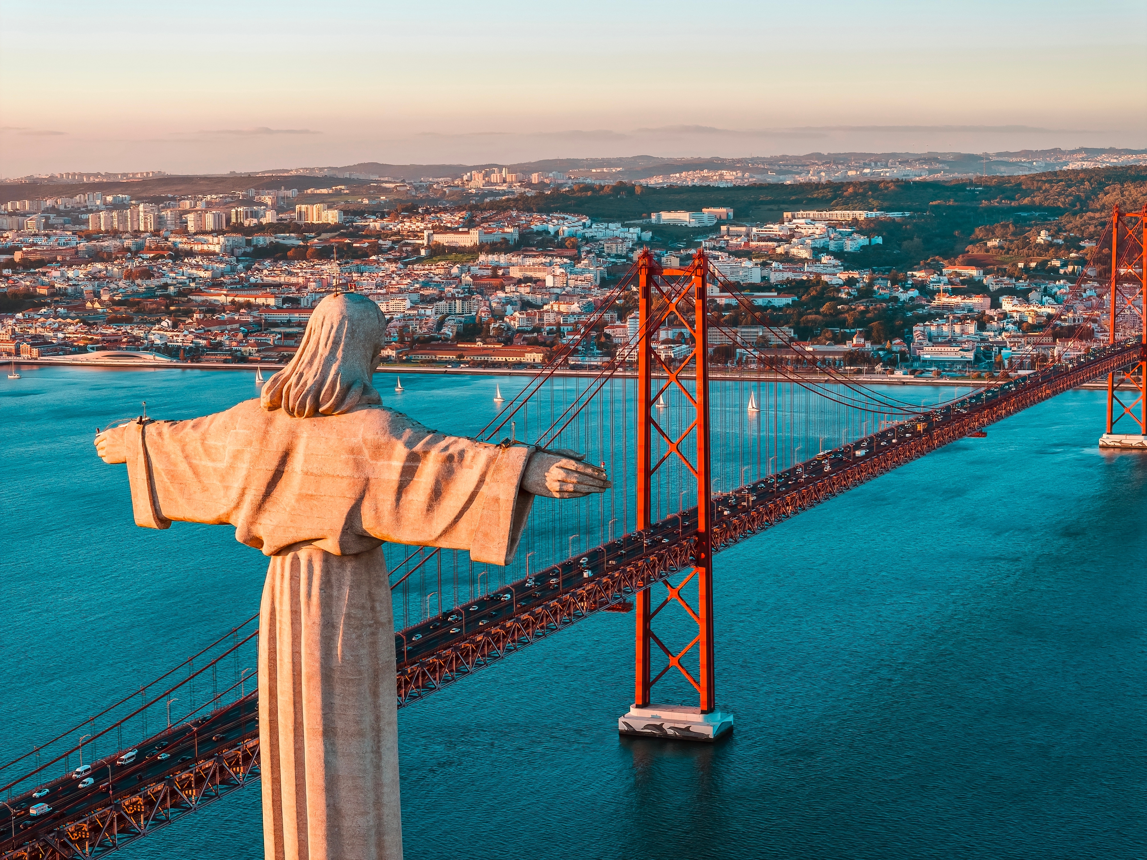 Drone billede af Cristo Rei helligdom og Ponte 25 de Abril bro i gyldent aftenlys